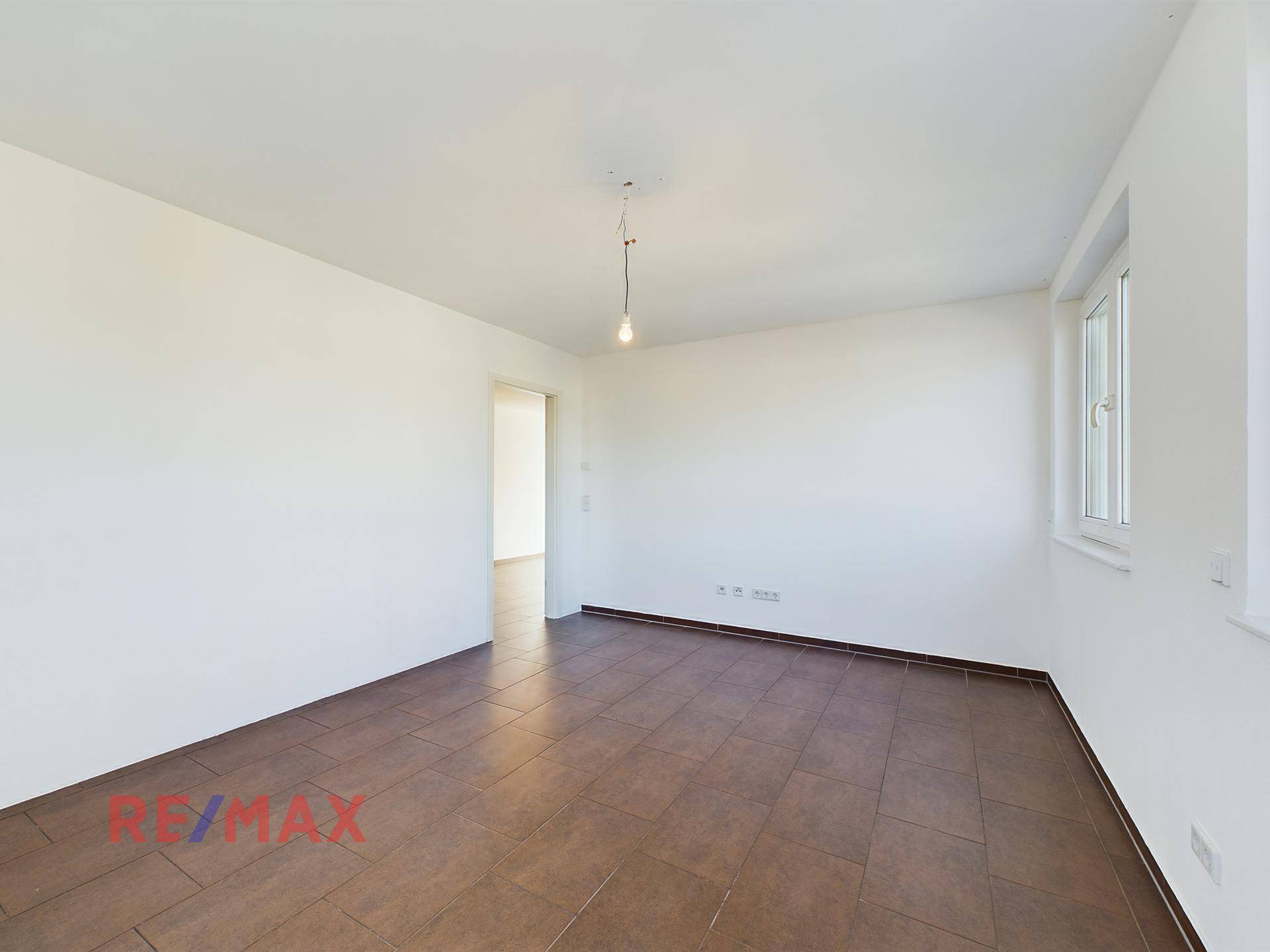 Geräumiges Zimmer mit Fliesenboden und viel Tageslicht durch das Fenster.
