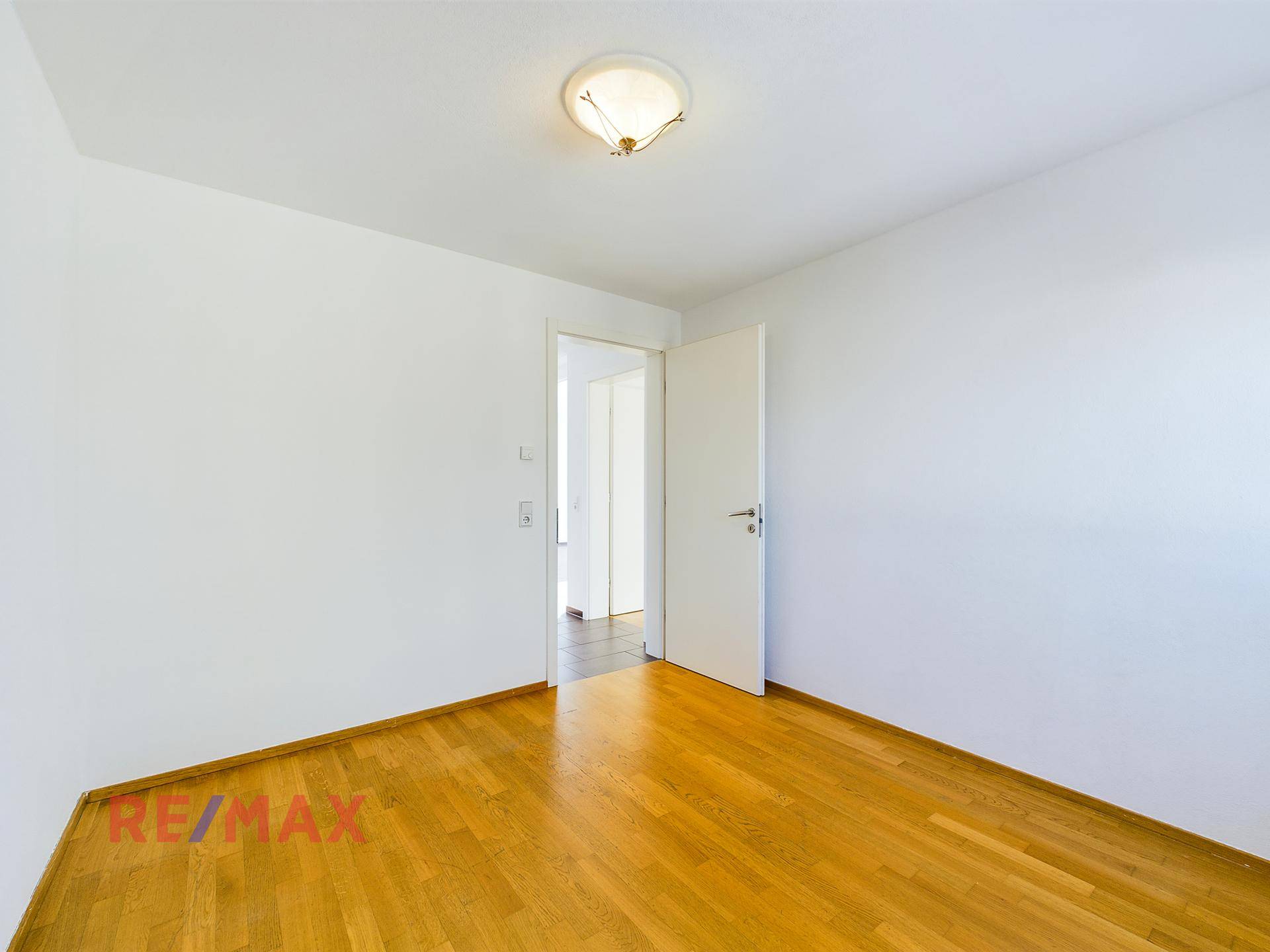 Schlafzimmer mit Parkettboden und Zugang zu einem weiteren Raum.