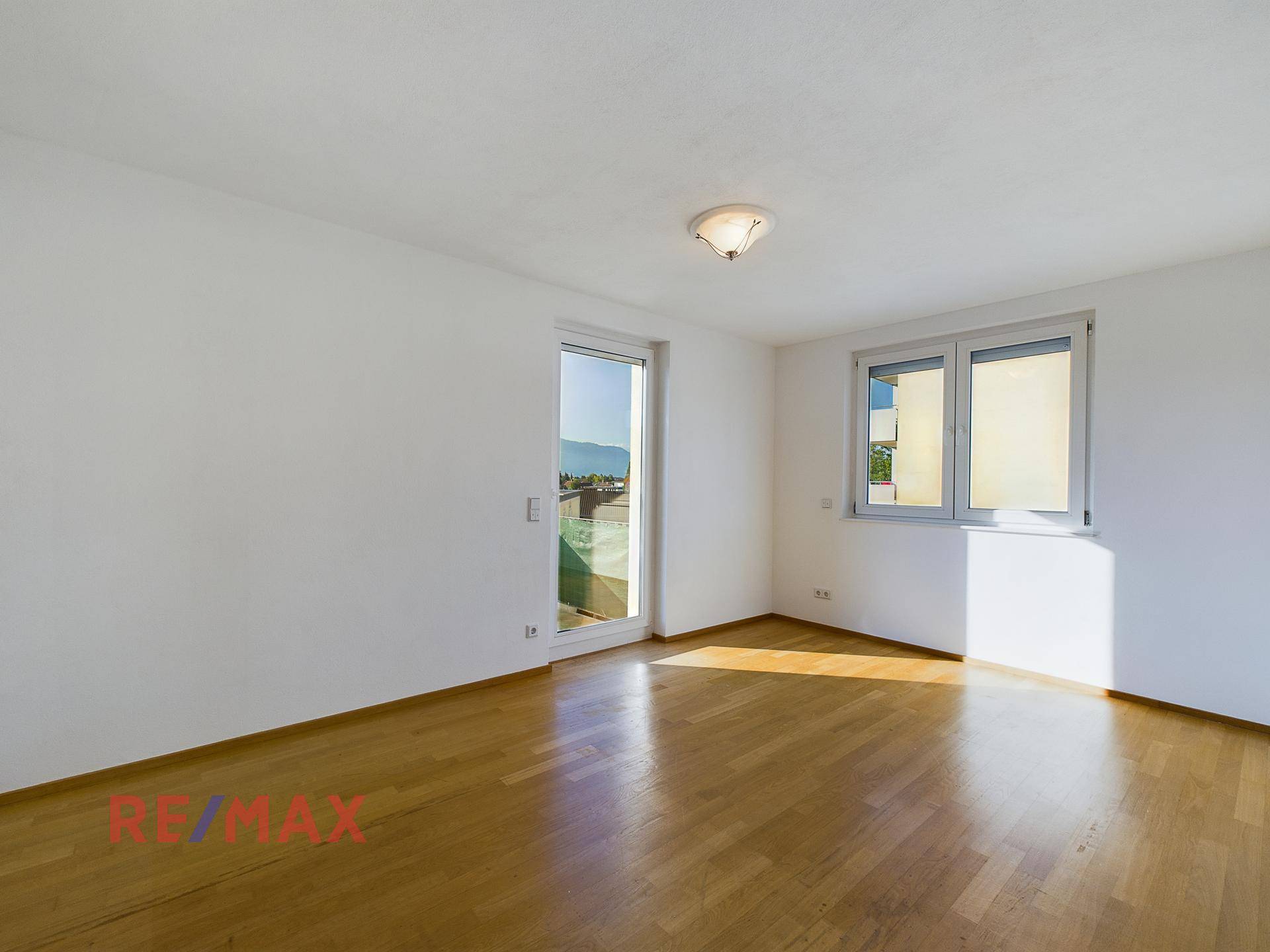 Helles Schlafzimmer mit Parkettboden und Zugang zum Balkon.