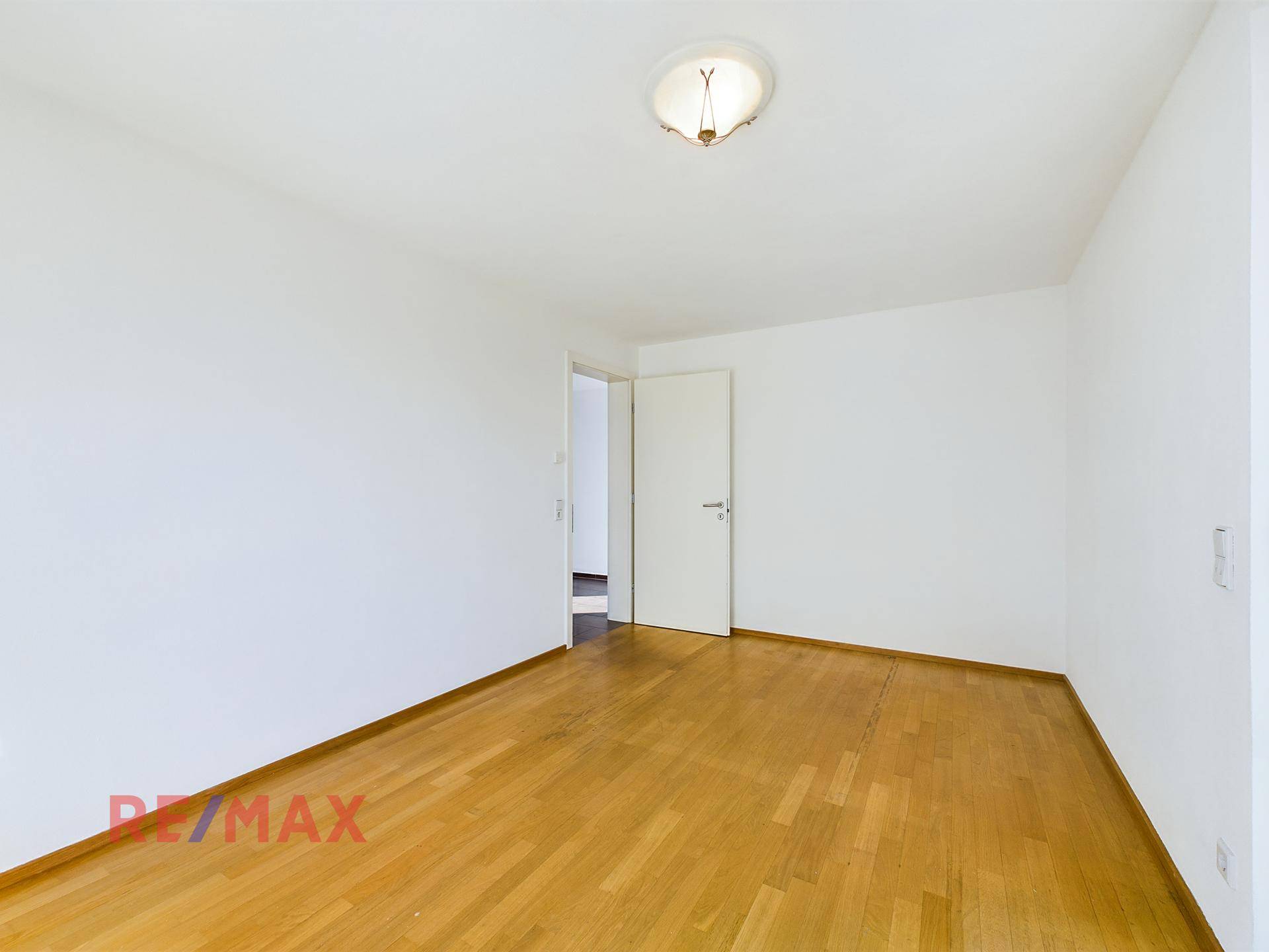 Geräumiges Schlafzimmer mit Parkettboden und viel Tageslicht.