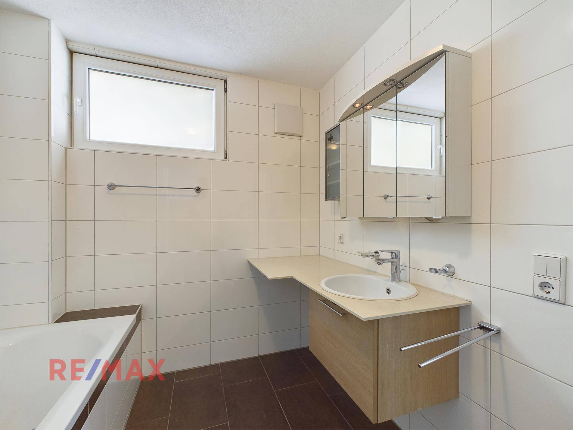 Badezimmer mit Waschbecken, Spiegelschrank und Fenster.