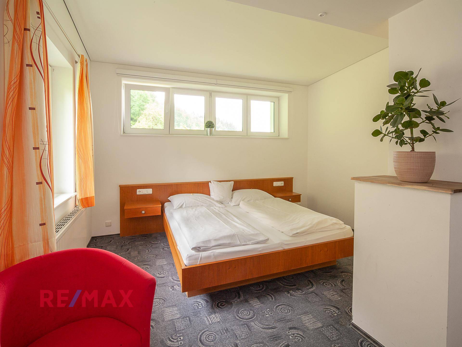 Schlafzimmer mit schwebendem Holzbett, Teppichboden und einem Fenster, das viel Licht spendet.