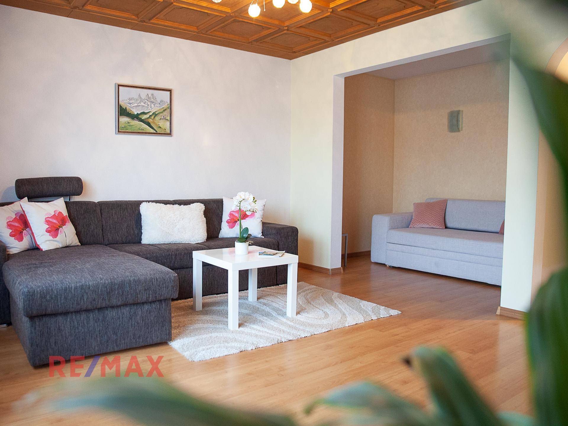 Gemütliches Wohnzimmer mit großem Ecksofa, Couchtisch und Holzkassettendecke.
