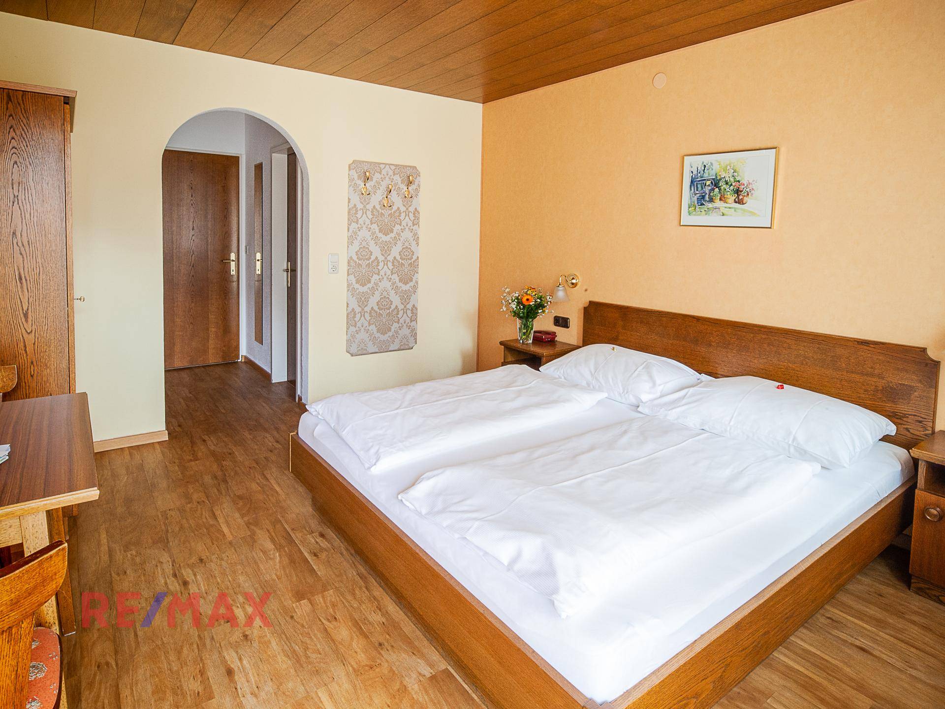 Schlafzimmer mit Doppelbett, Holzboden und Zugang zu einem angrenzenden Badezimmer.