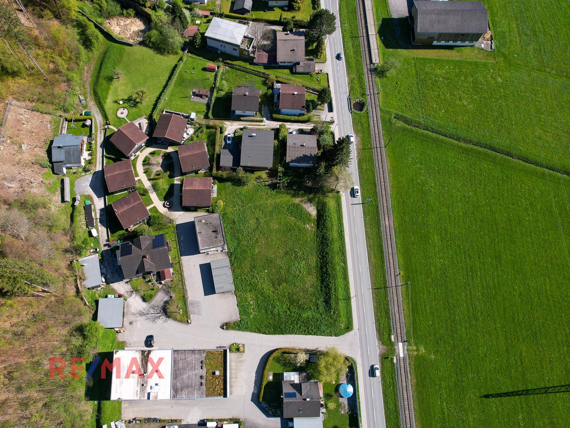 Senkrechte Luftaufnahme des grünen Grundstücks mit angrenzender Straße und benachbarten Wohnhäusern.