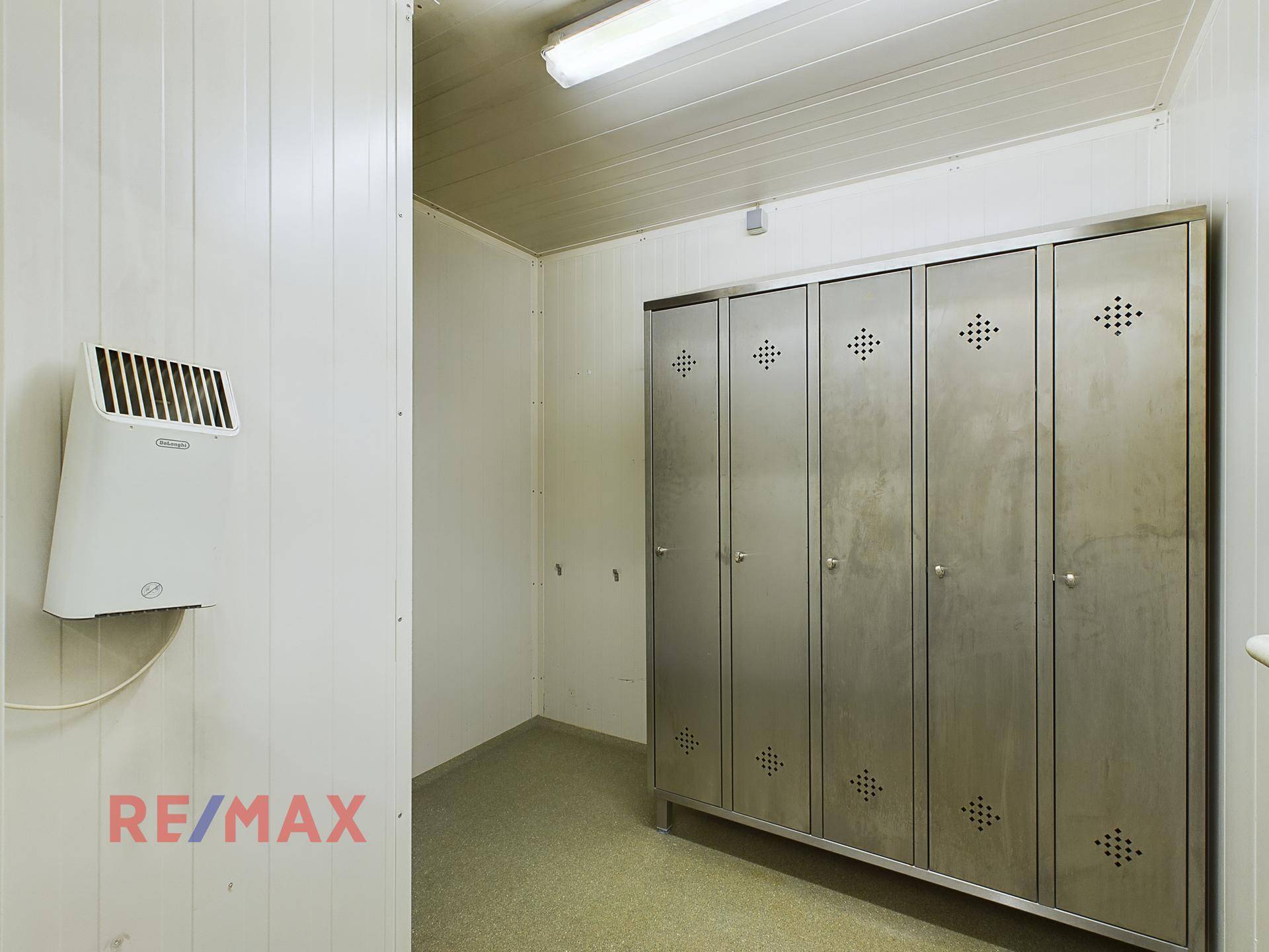 Umkleideraum mit Metallschränken und einem Wandheizgerät, ideal für Mitarbeiter.