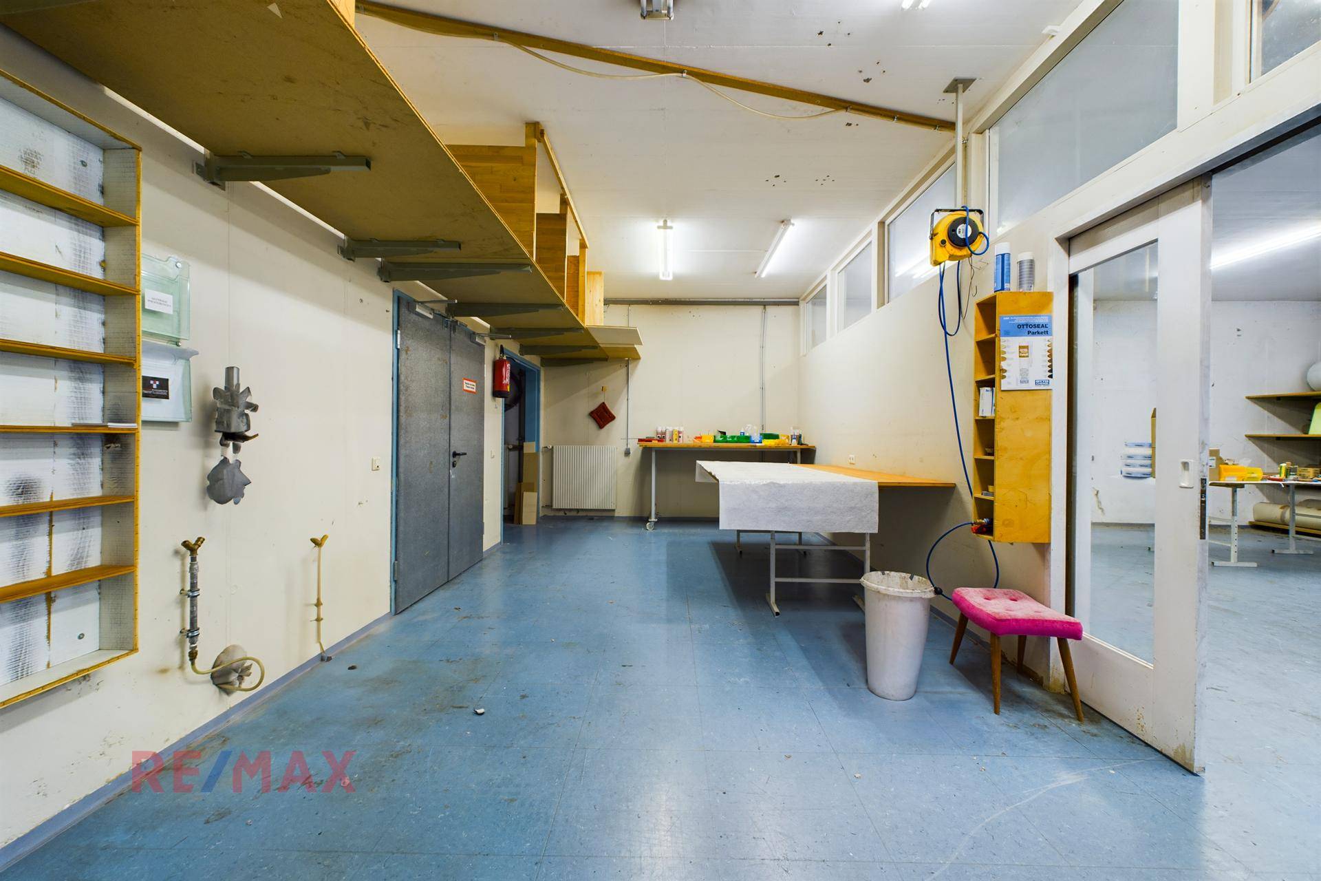 Werkstattbereich mit Arbeitstischen, Regalen und einem robusten Boden für handwerkliche Tätigkeiten.