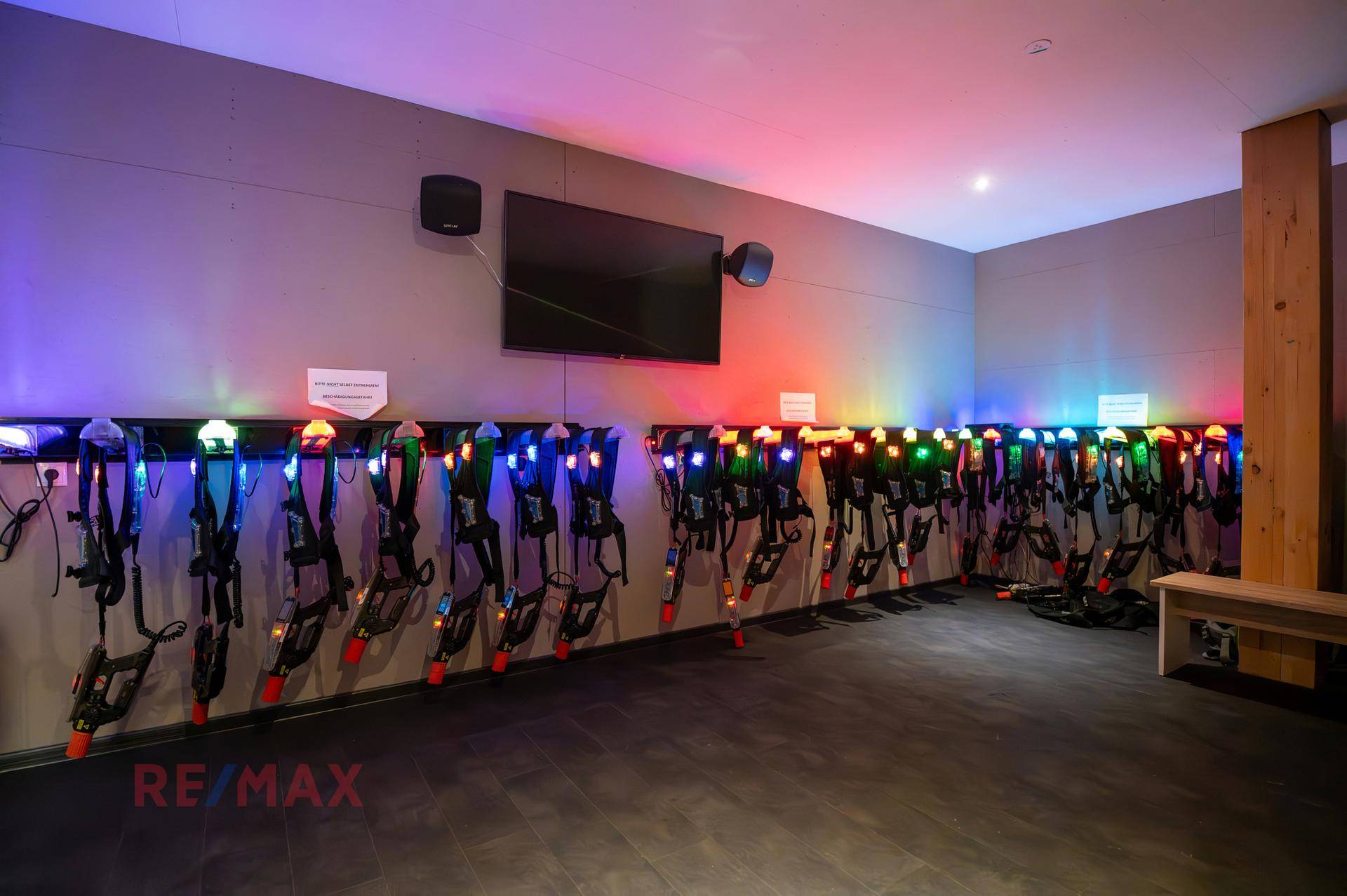 Raum zur Ausgabe von Laser-Tag-Ausrüstung mit farbiger Beleuchtung und Wandhalterungen.