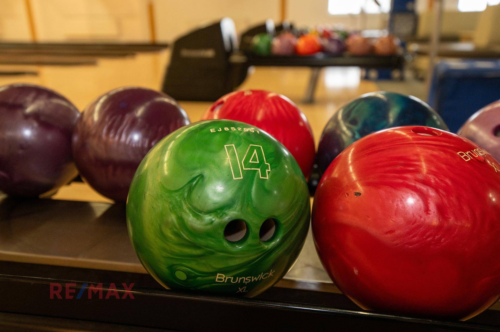 Nahaufnahme von bunten Bowlingkugeln, bereit für das Spiel in einer Freizeitanlage.