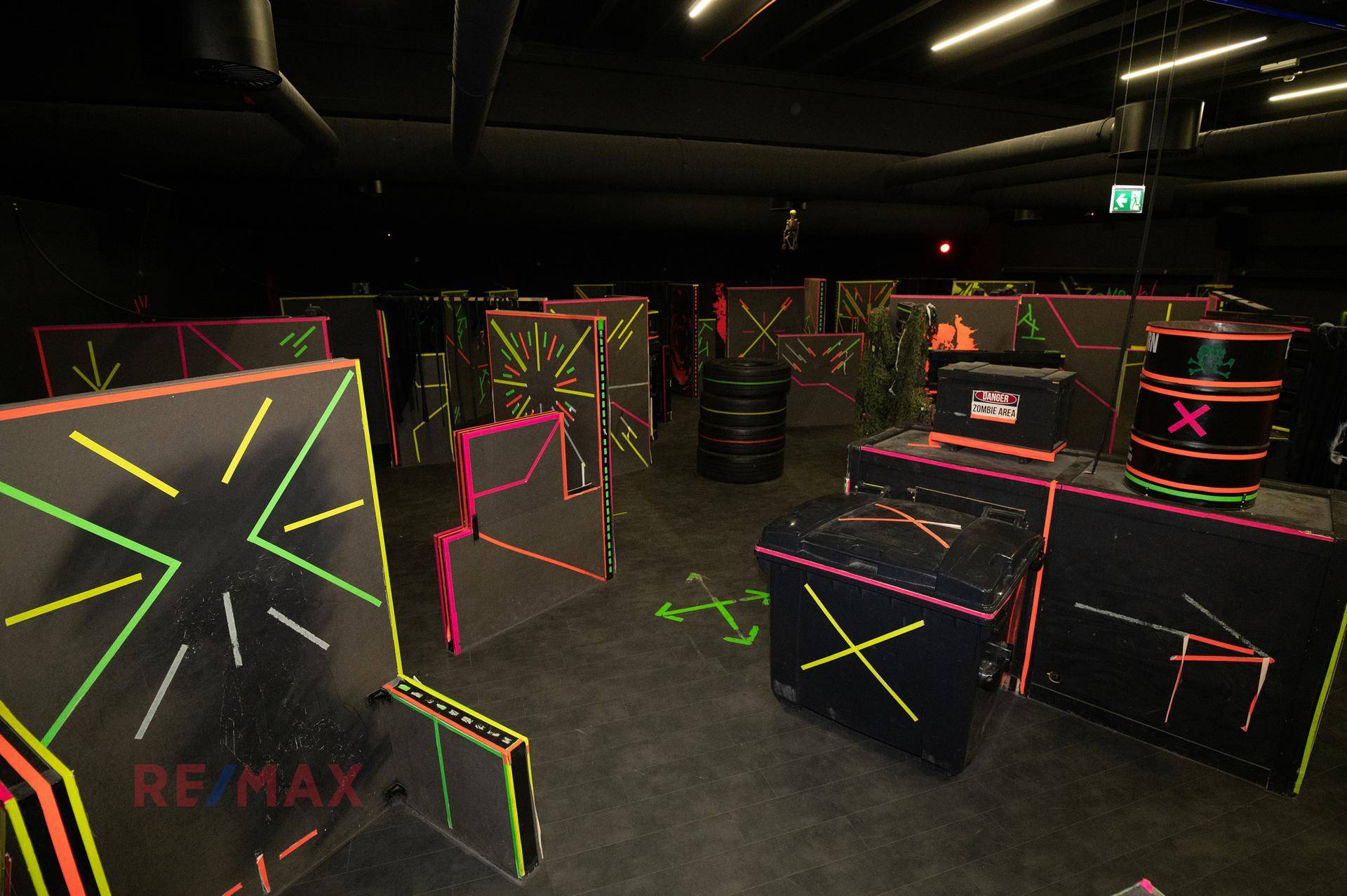Dunkle Laser-Tag-Arena mit leuchtenden Hindernissen und Neonakzenten für ein spannendes Spielerlebnis.