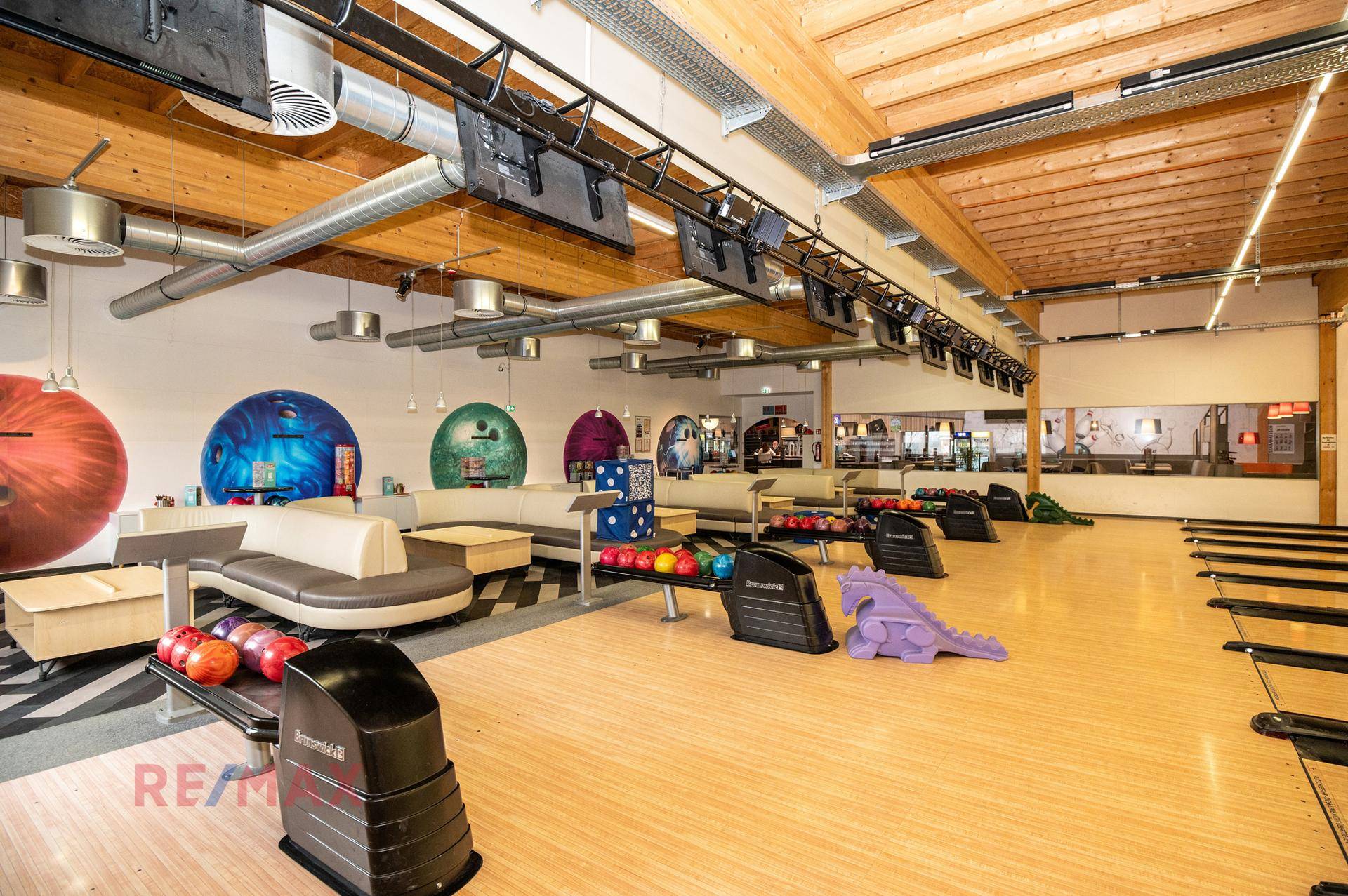 Mehrere Bowlingbahnen mit Holzboden, Sitzgelegenheiten und Bildschirmen für die Spielanzeige.