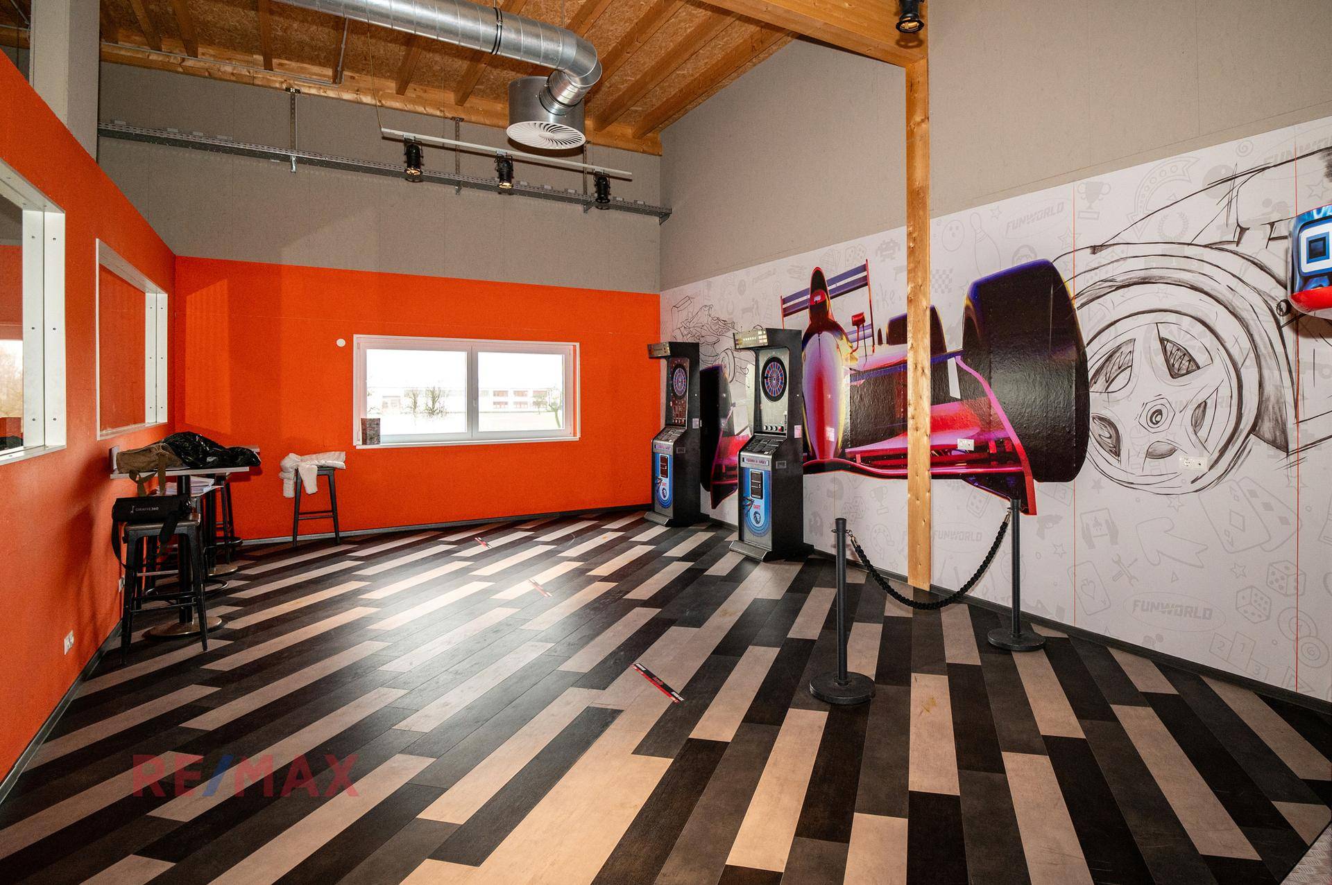 Spielzimmer mit Arcade-Automaten, farbigen Wänden und gemustertem Boden für Unterhaltung.
