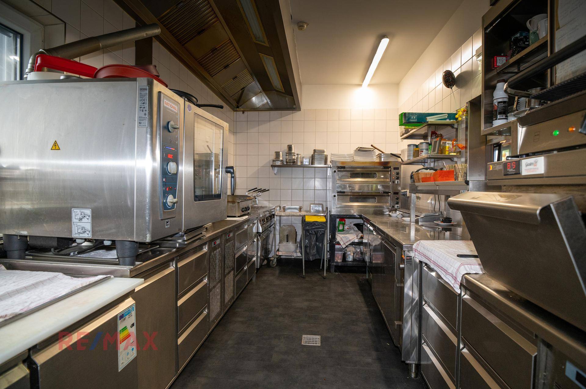 Professionelle Großküche mit Edelstahlgeräten, Fliesenwänden und Abluftsystem für den Gastronomiebetrieb.