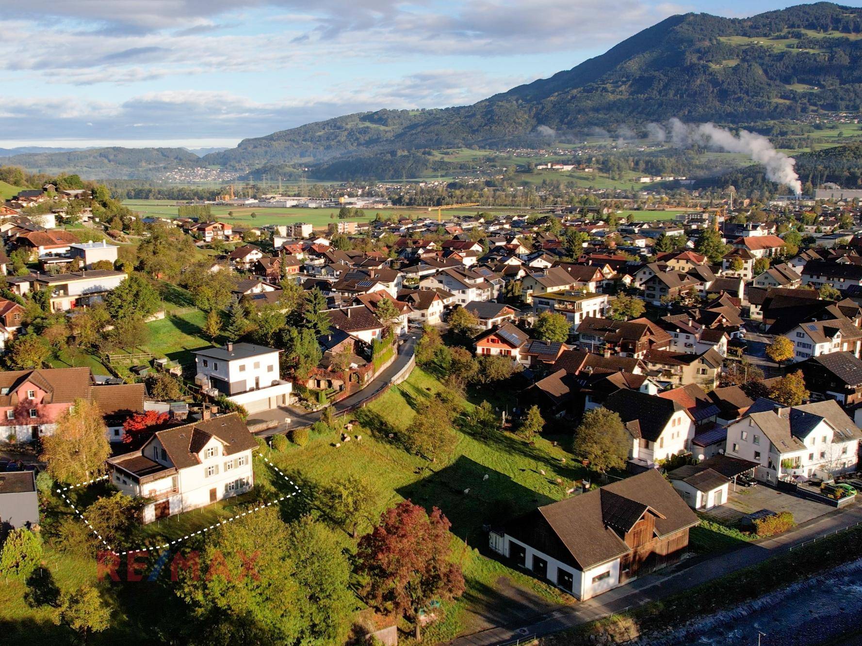 Weitläufige Luftaufnahme des Hauses in ländlicher Umgebung mit Bergen im Hintergrund.