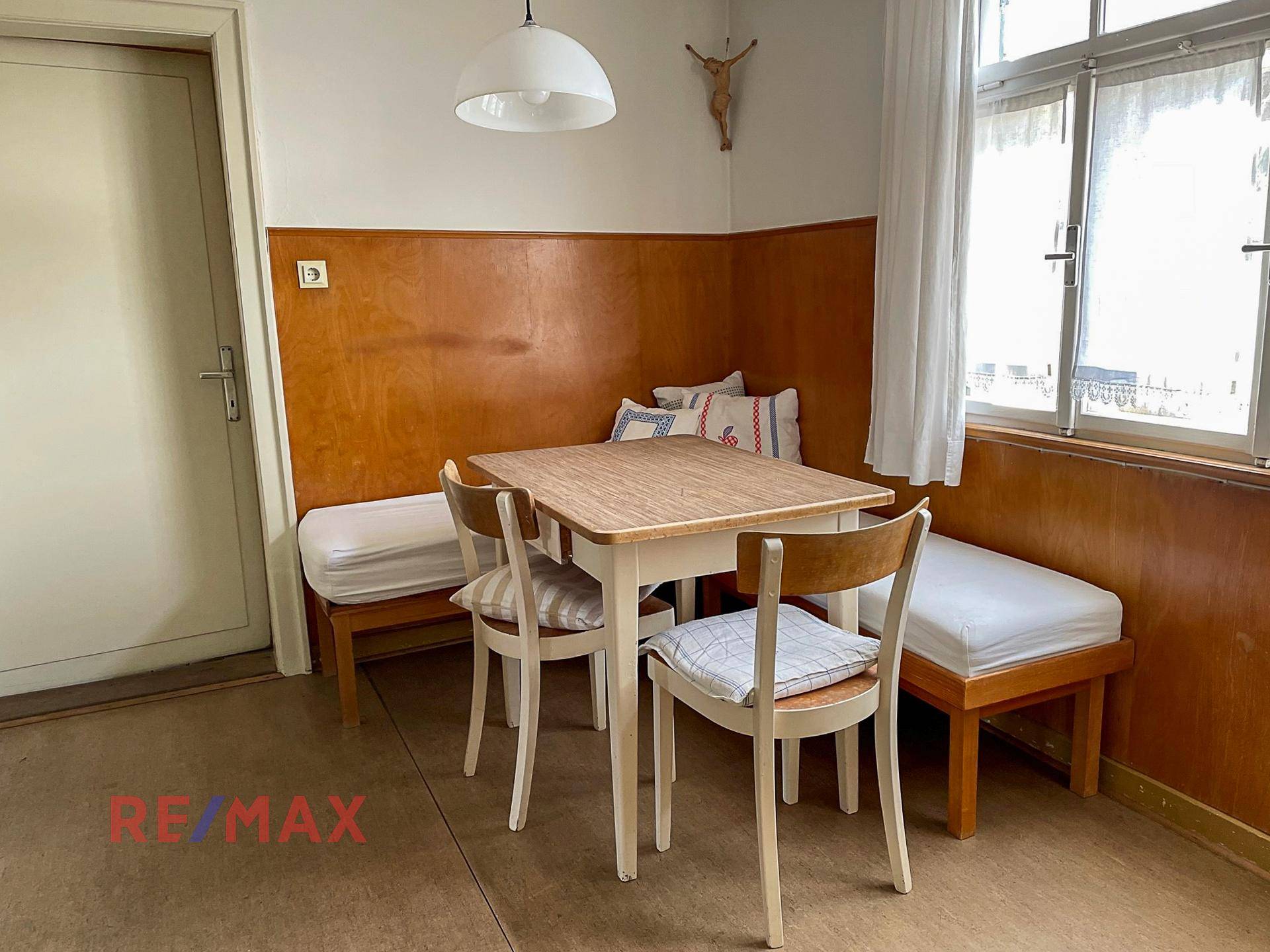 Gemütlicher Essbereich in der Küche mit Holzbänken, Tisch und Fensterblick ins Grüne.