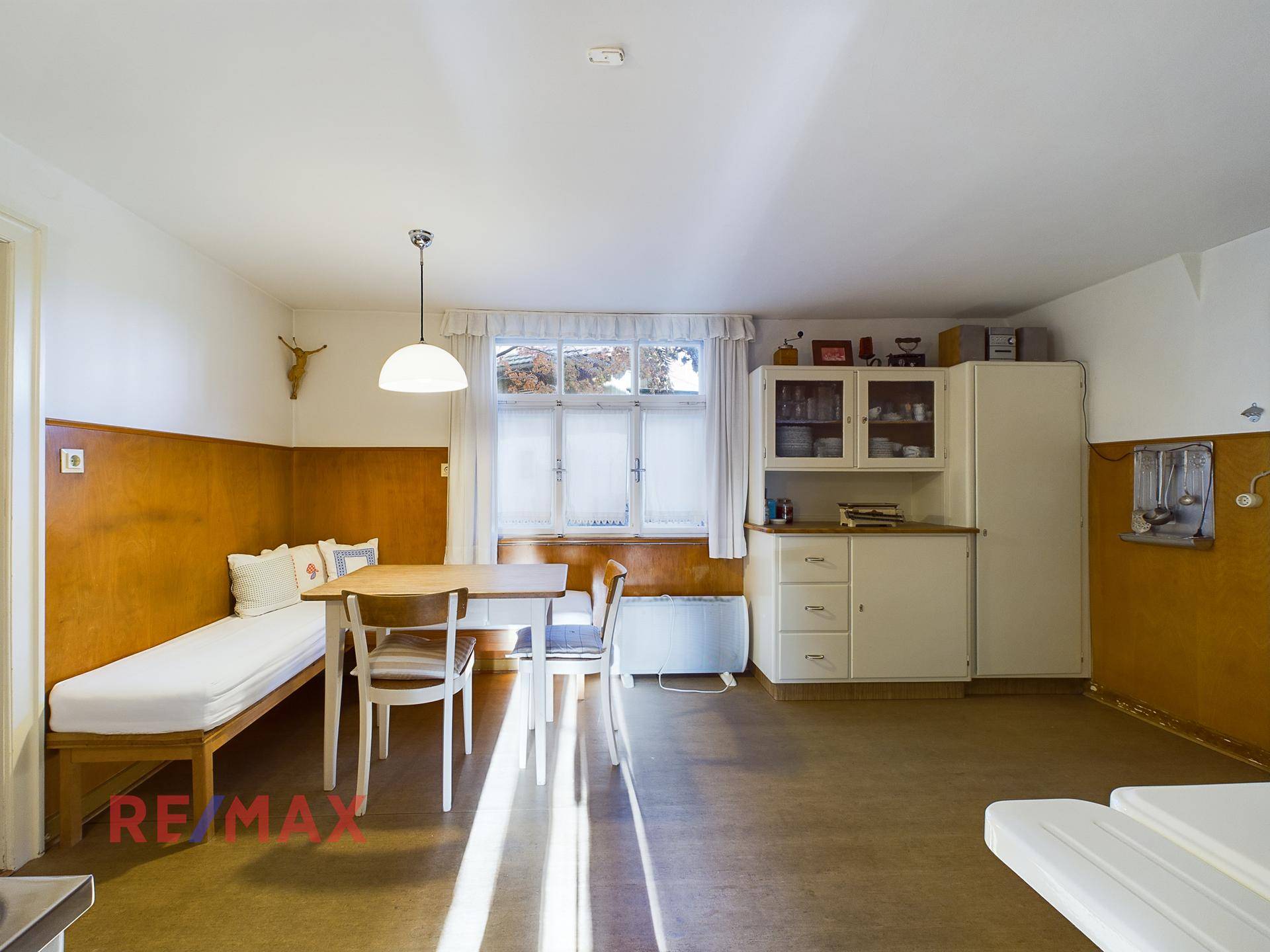 Funktionale Küche mit Essplatz, Einbauschränken und Blick durch das Fenster.