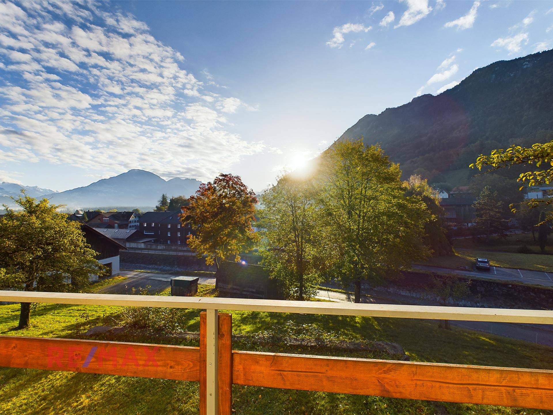 Sonniger Ausblick von einem Balkon auf die umliegende Berglandschaft und das Tal.