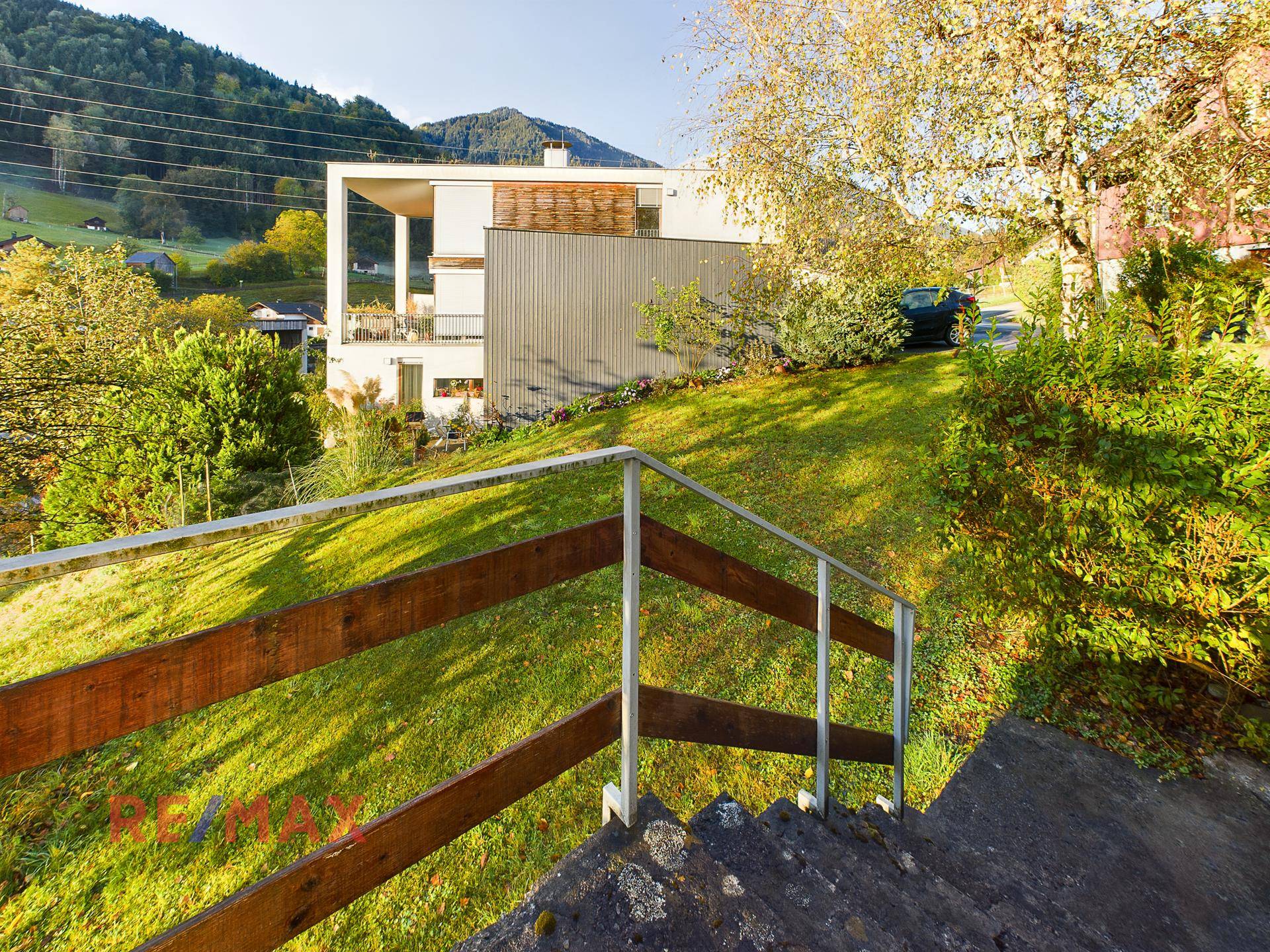 Blick über eine grüne Wiese auf ein modernes Gebäude mit klaren Linien und viel Grün.