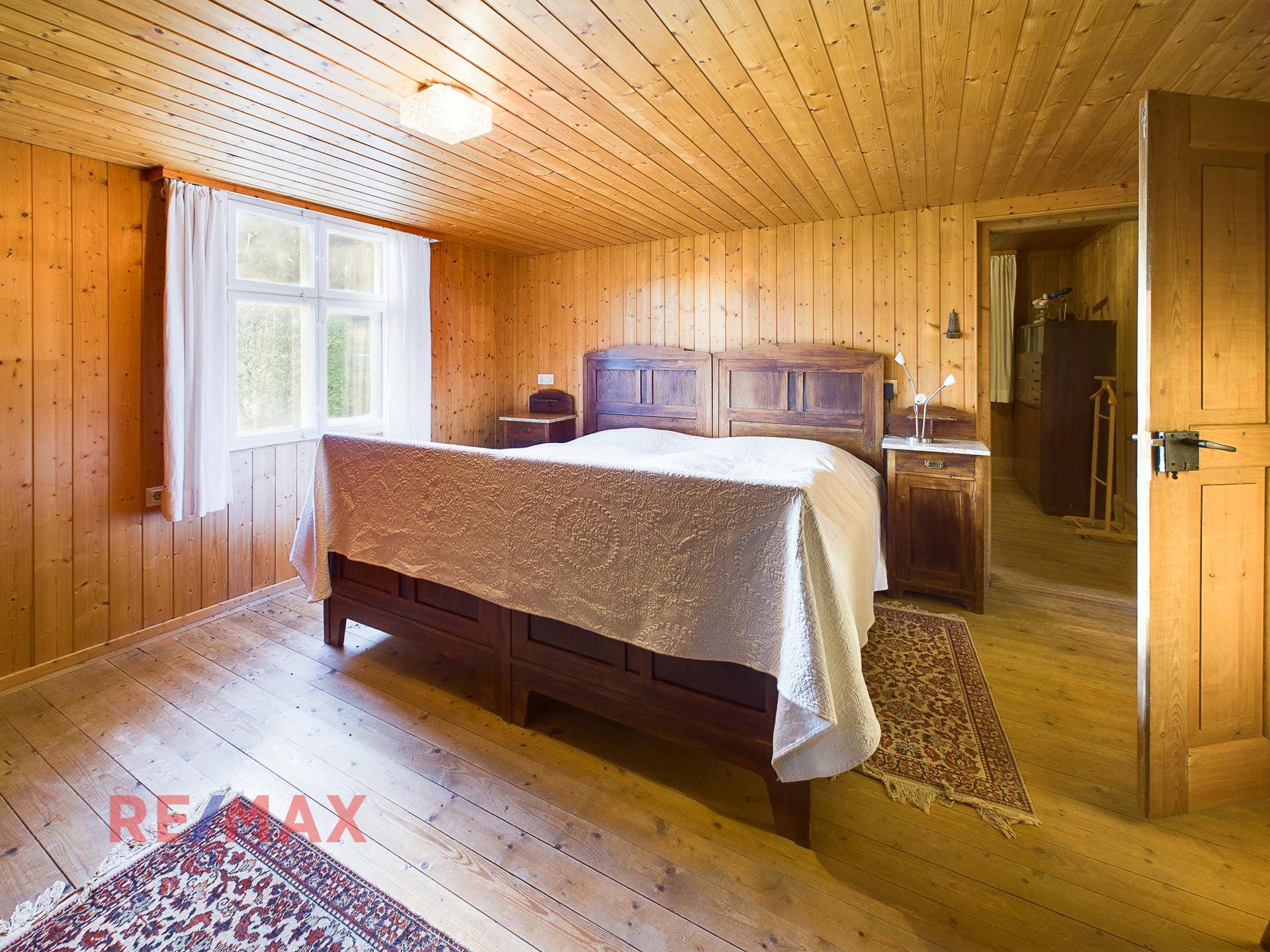 Geräumiges Schlafzimmer mit großem Holzbett, Holzboden und Fenster.