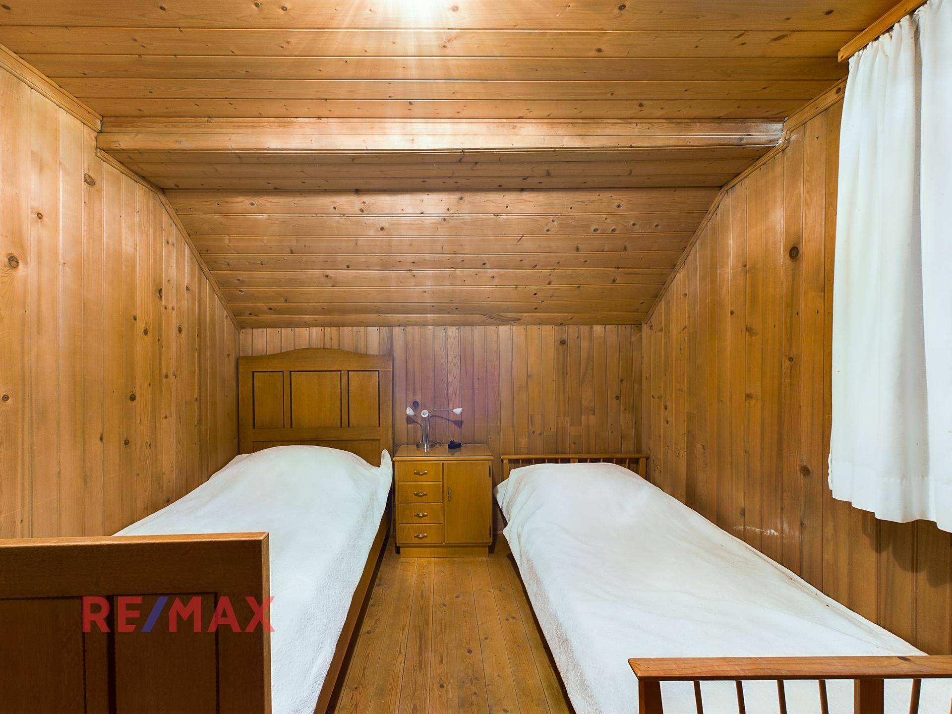 Schlafzimmer im Dachgeschoss mit zwei Einzelbetten, Holztäfelung und Dachschräge.