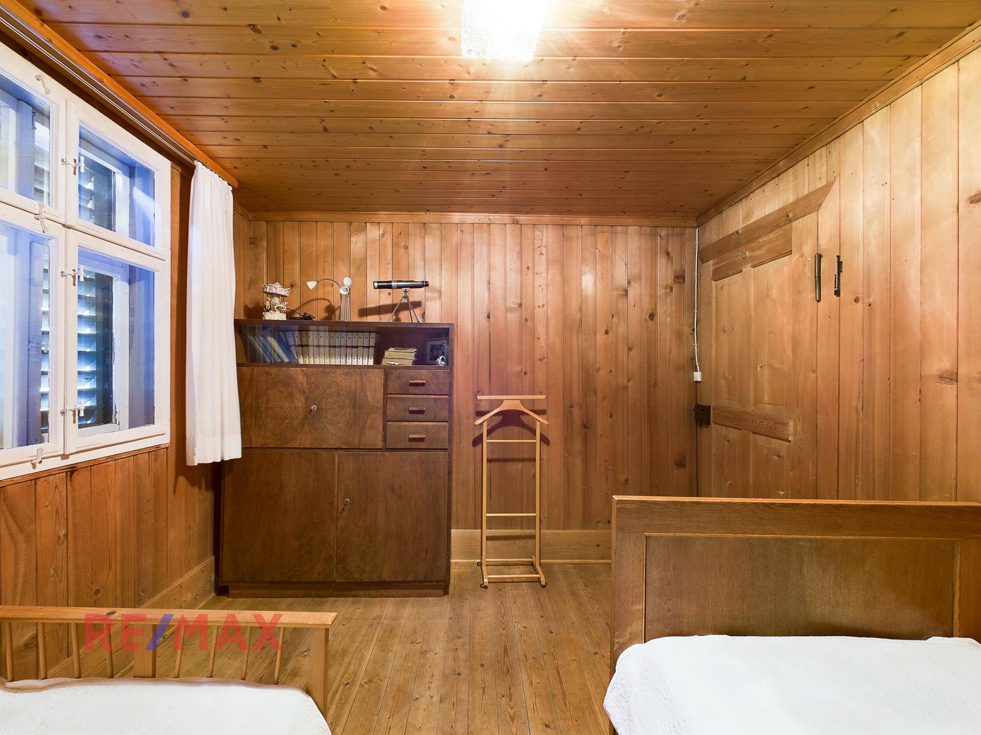 Helles Schlafzimmer mit zwei Einzelbetten, Holztäfelung und Stauraum.