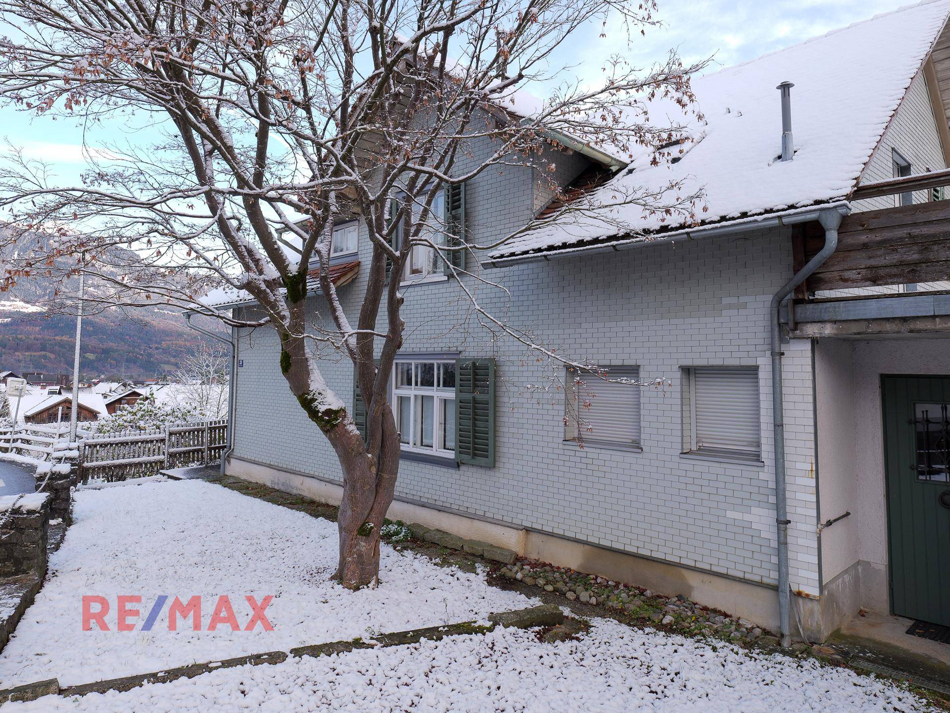 Fassade des Hauses im Winter mit Schnee auf dem Boden und den Bäumen.