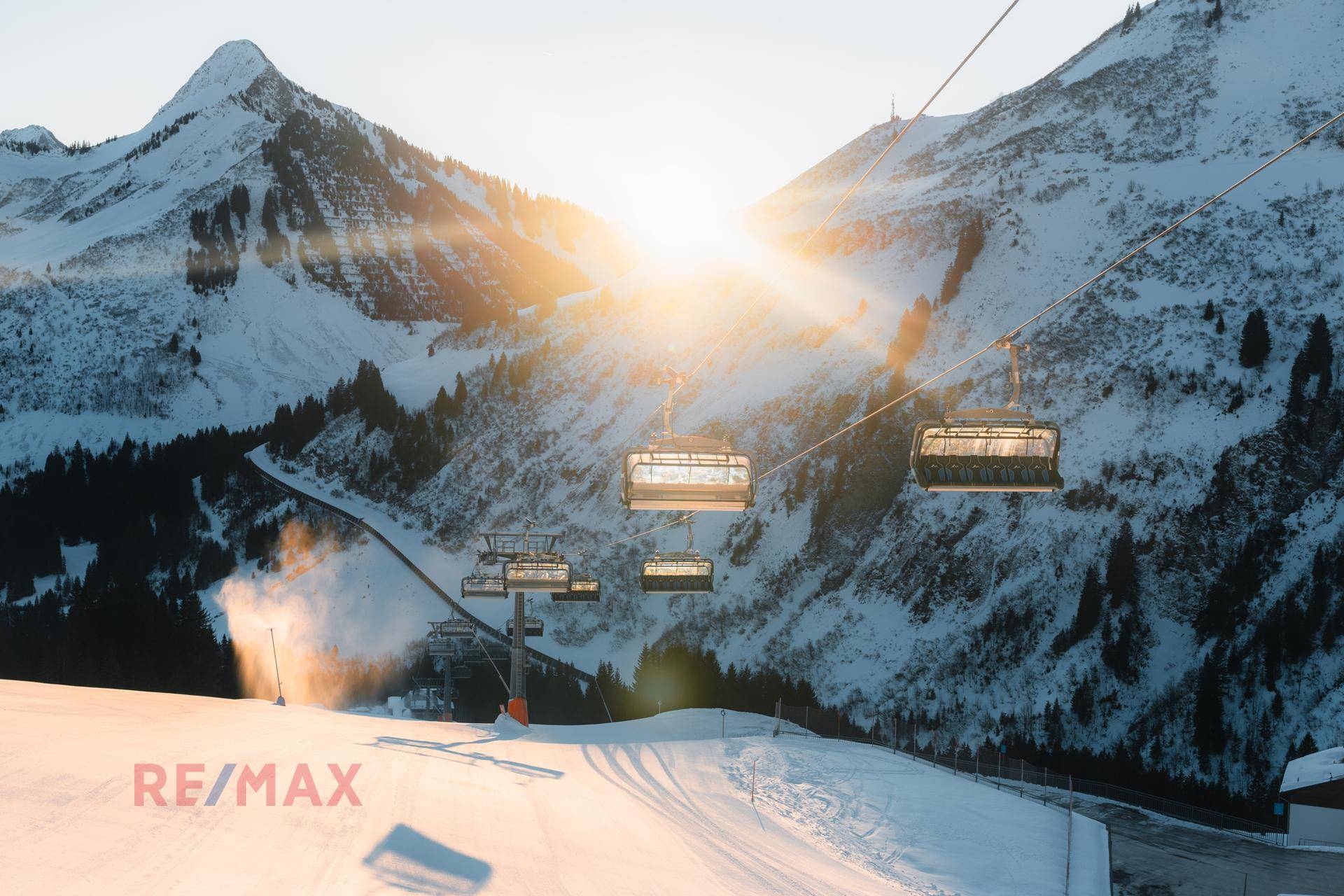 Skilift vor einer beeindruckenden Bergkulisse mit strahlendem Sonnenschein und verschneiten Pisten.