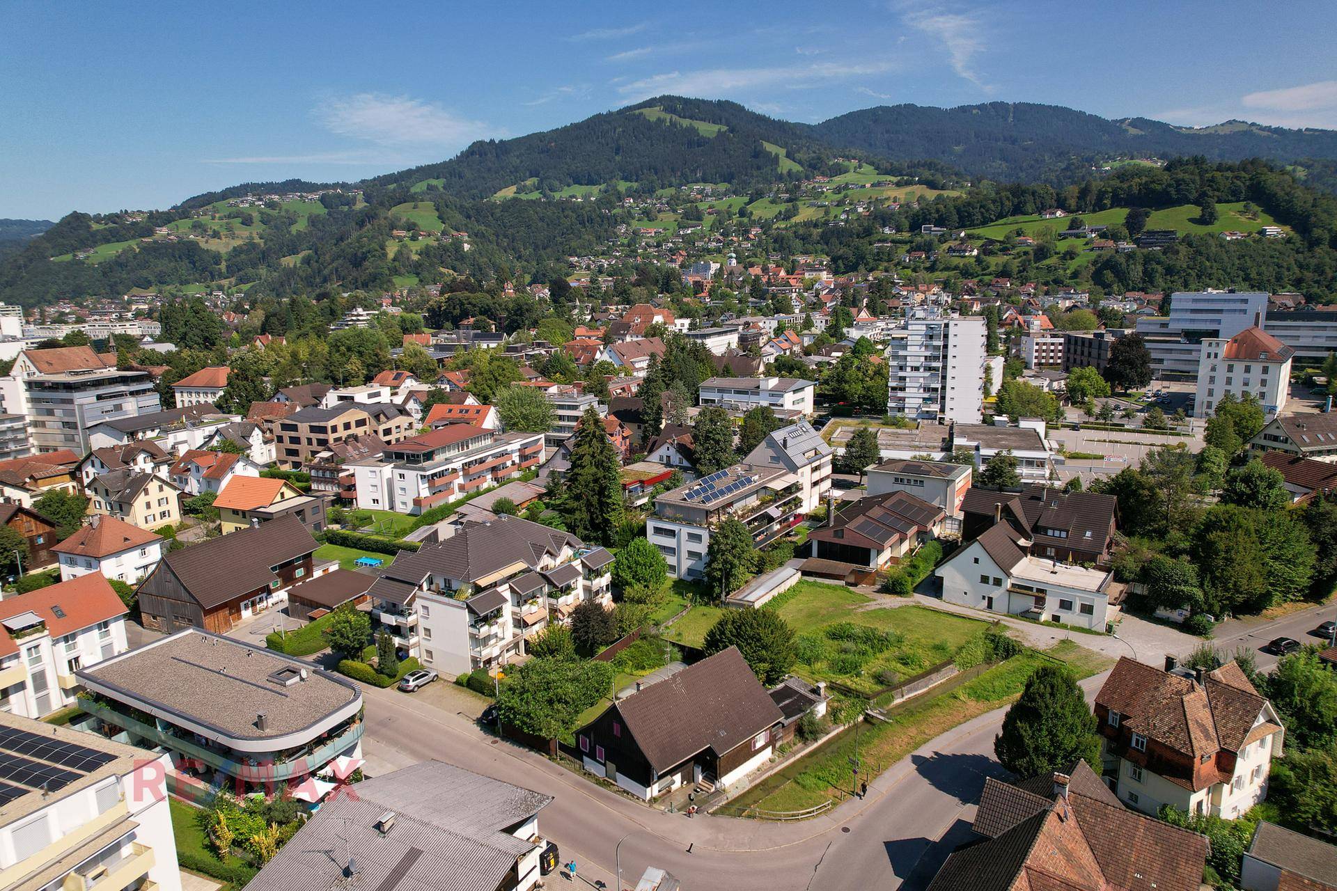 Weitläufige Luftaufnahme der Wohngegend mit Bergen und grüner Landschaft im Hintergrund.