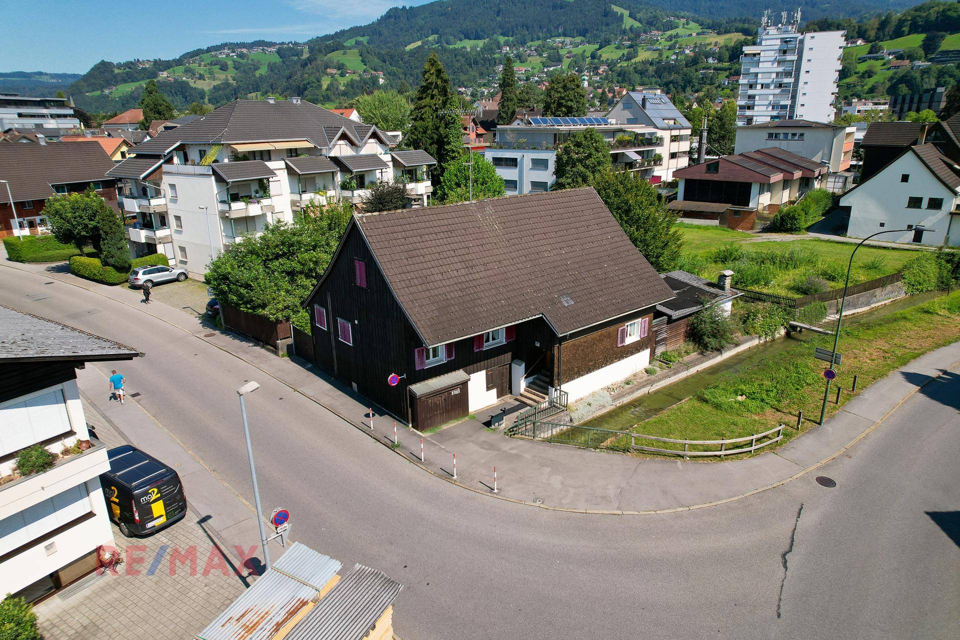 Luftaufnahme des Einfamilienhauses an einer Straßenecke mit Bergblick im Hintergrund.