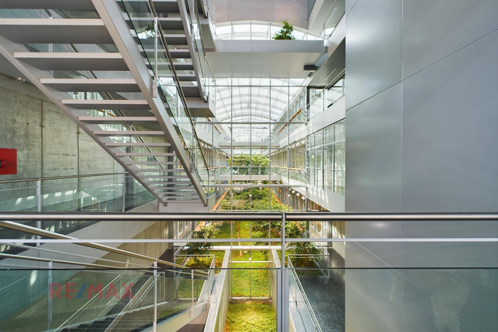 Beeindruckendes Atrium mit moderner Architektur, Glasdach und offener Treppenkonstruktion über mehrere Ebenen.
