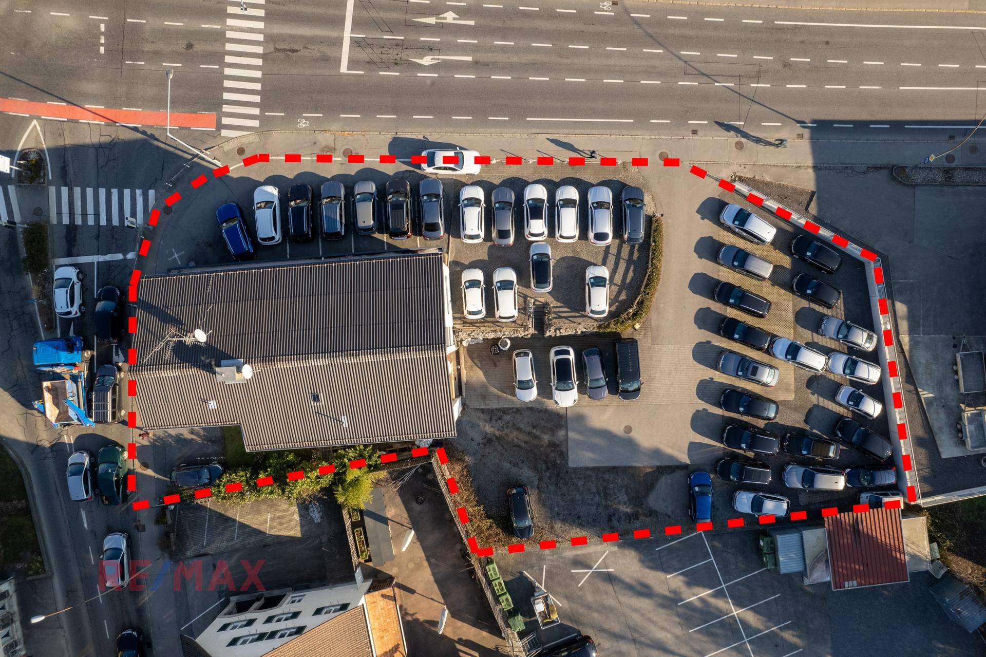 Detaillierte Luftaufnahme des Grundstücks mit Gebäude und großem Parkplatz, umrandet von Straßen.