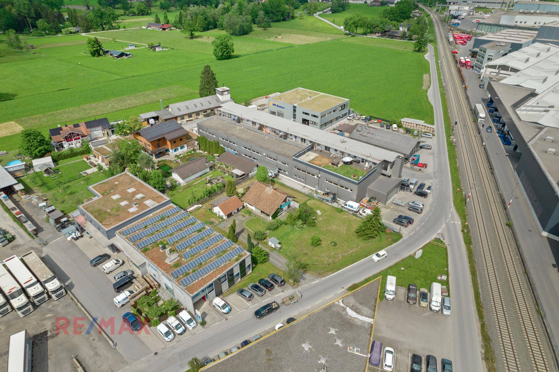 Luftbild des Grundstücks in einer Gewerbezone, umgeben von weiteren Gebäuden, Straßen und grüner Landschaft.