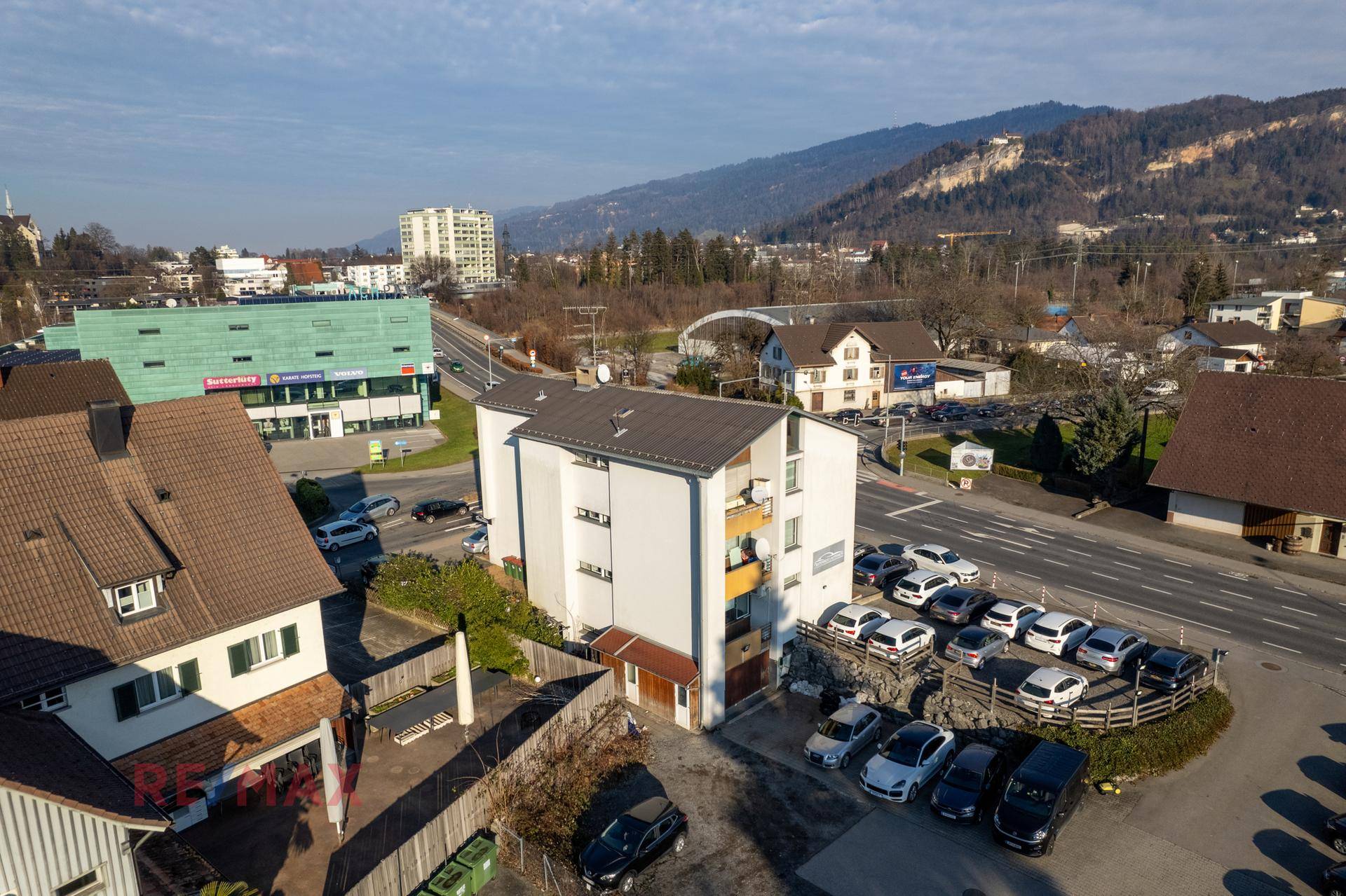 Luftaufnahme des Hauptgebäudes mit Parkplätzen und Blick auf die umliegende Berglandschaft.