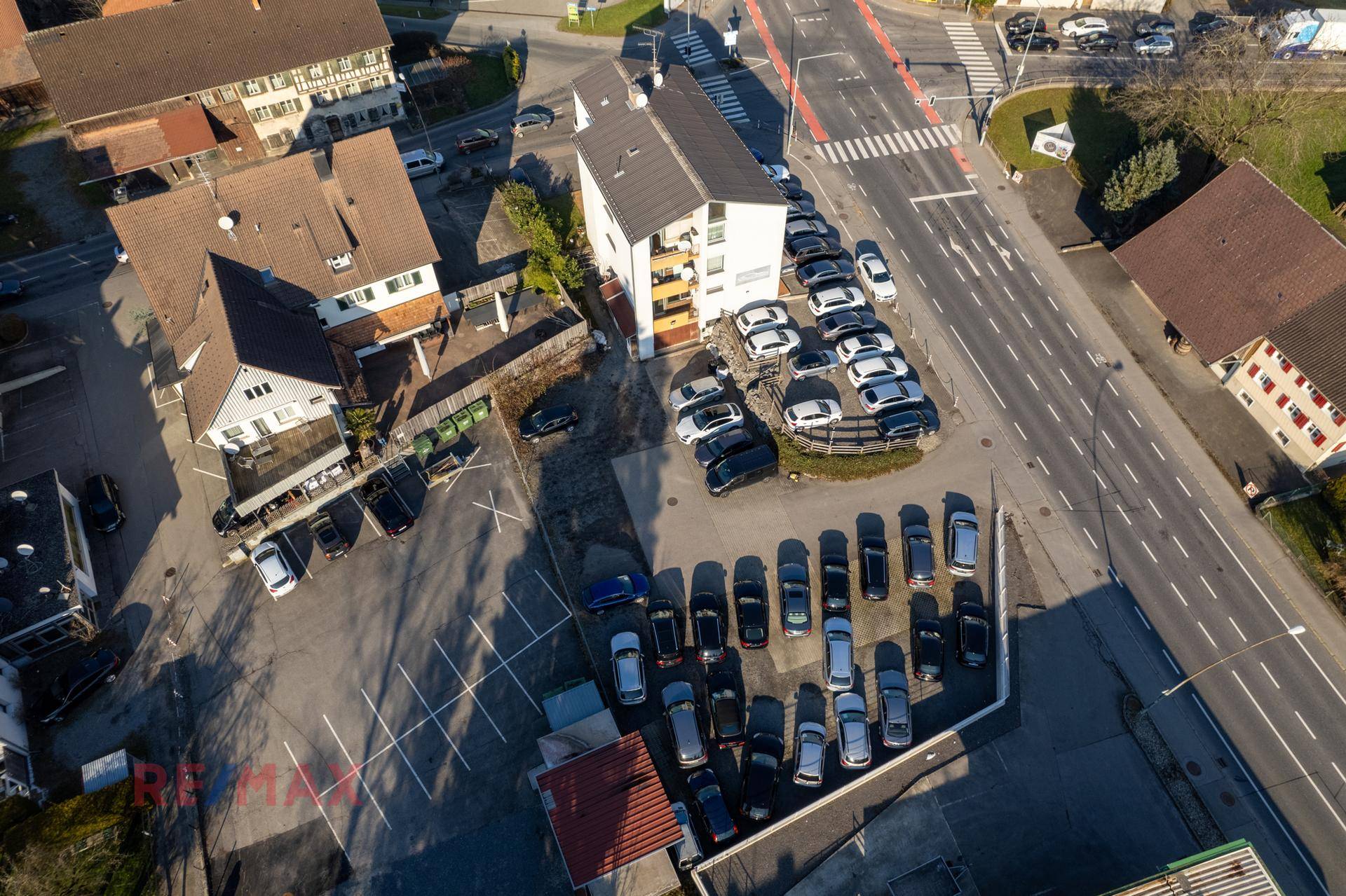 Detaillierte Luftaufnahme des Grundstücks mit Gebäude und ausgedehntem Parkbereich für Fahrzeuge.
