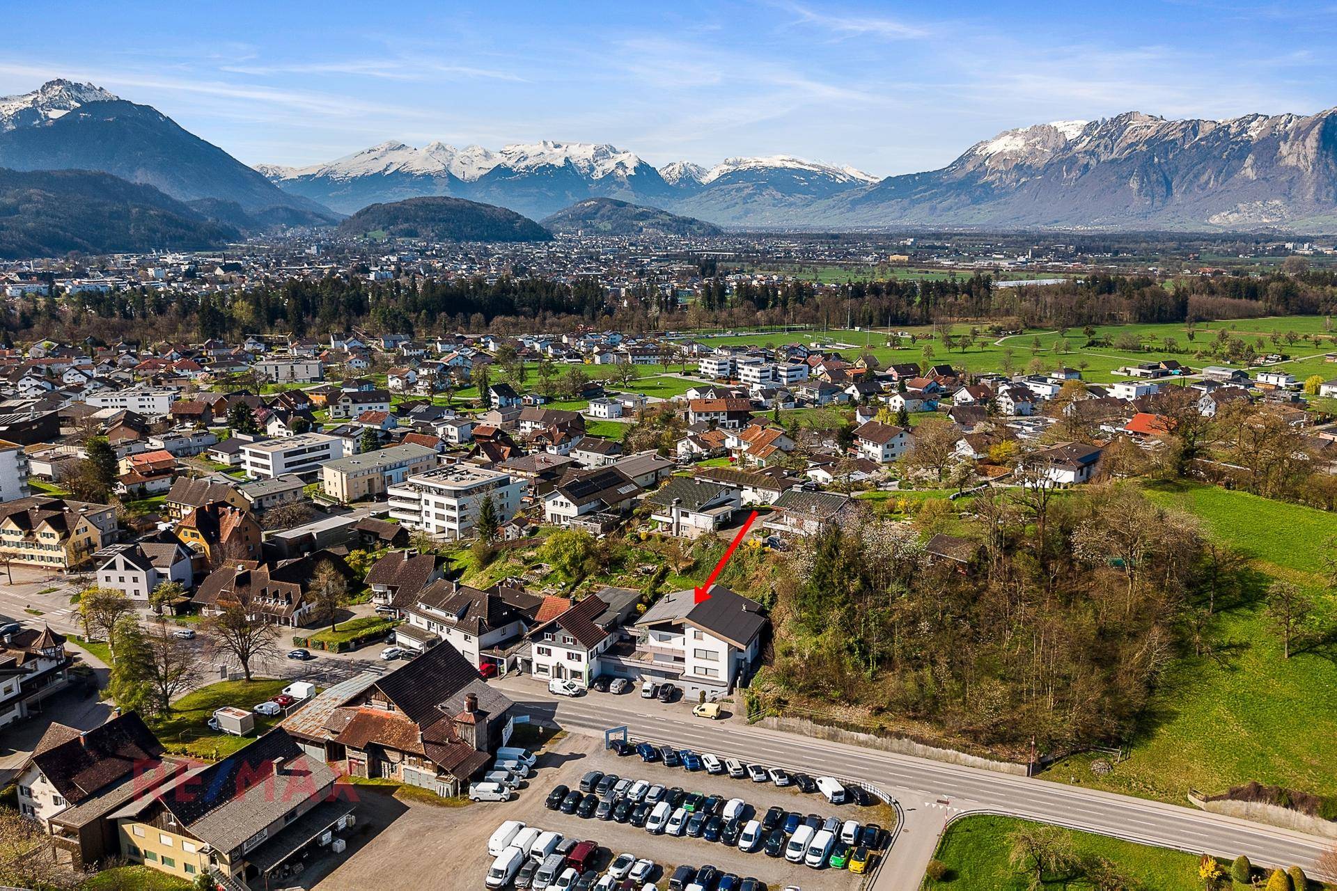 Luftaufnahme des Anwesens mit umliegender Bebauung und beeindruckendem Bergpanorama im Hintergrund.