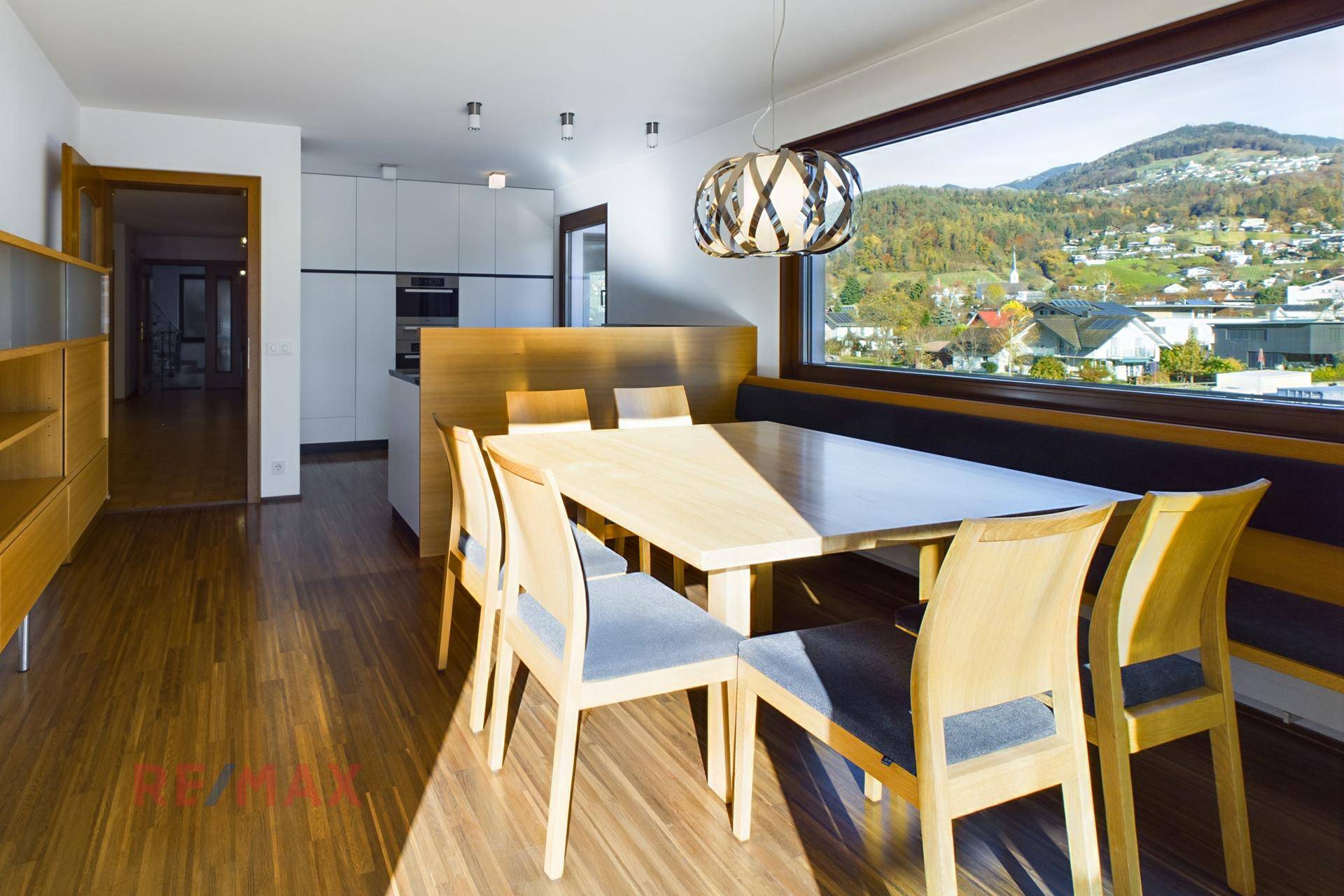 Heller Essbereich mit Holztisch, Sitzbank und weitem Blick auf die hügelige Landschaft.