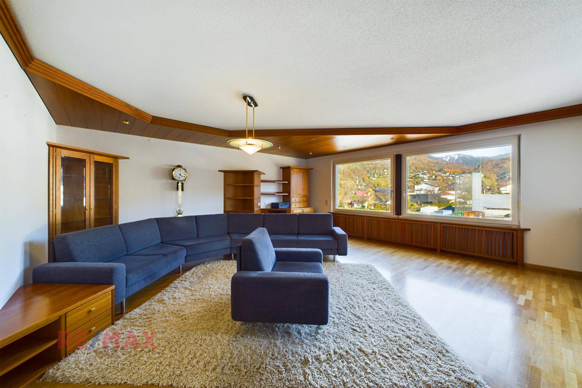 Geräumiges Wohnzimmer mit Parkettboden, großer Couch und weitem Blick auf die Umgebung.