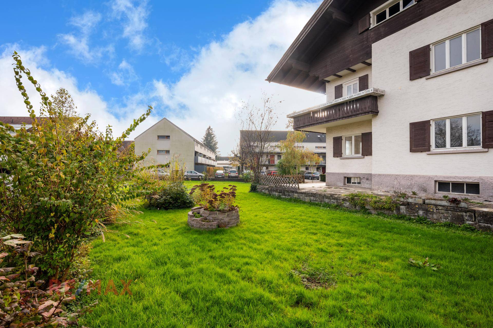 Seitlicher Gartenbereich des Hauses mit Rasenfläche und dekorativen Pflanzen.
