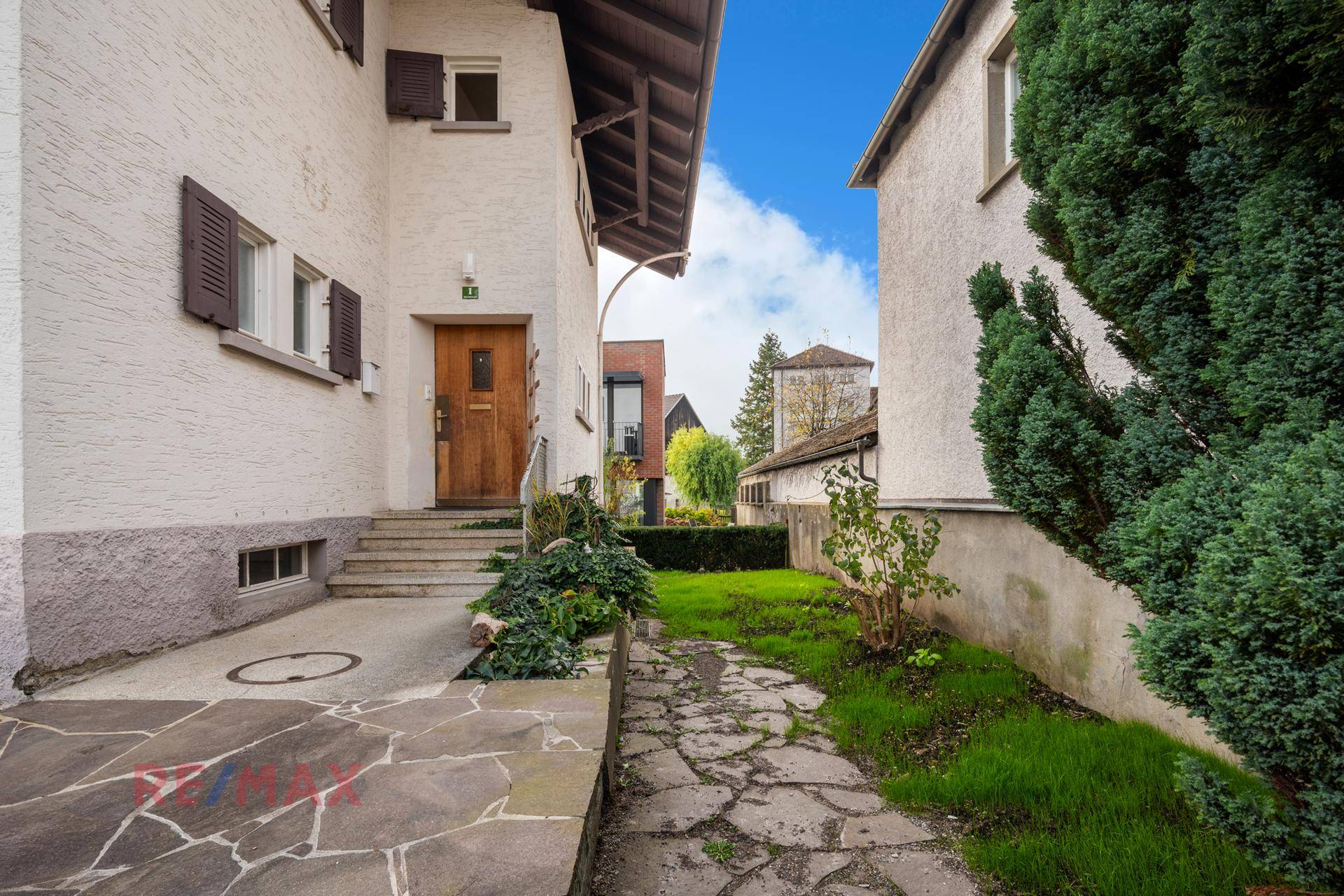 Eingangsbereich des Hauses mit Steintreppe und gepflastertem Weg durch den Vorgarten.