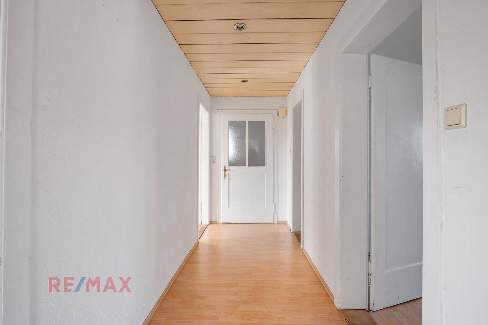 Heller Flur mit Holzdeckenverkleidung und Laminatboden.