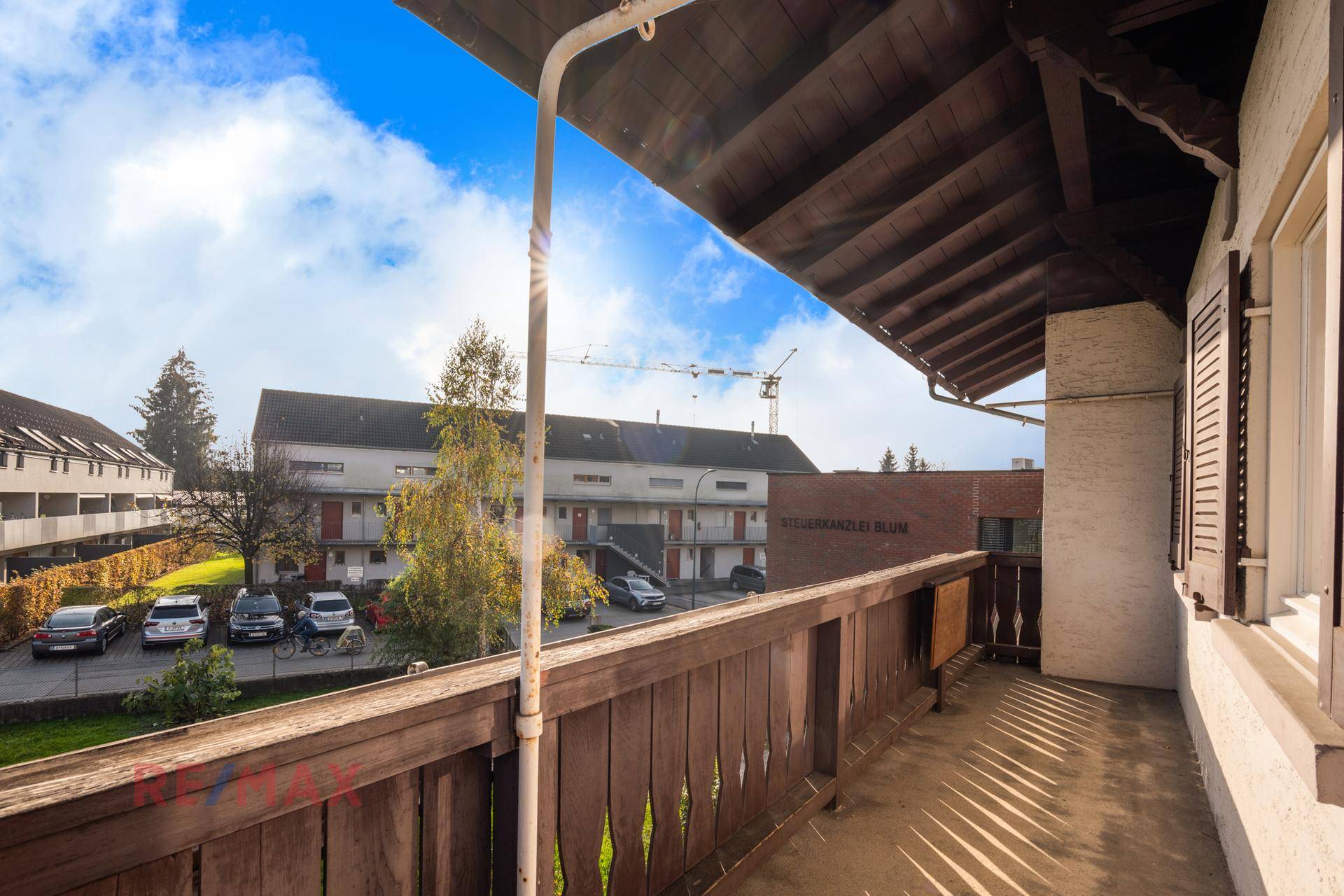 Kleiner Balkon mit Holzgeländer und Blick auf die Nachbarschaft.