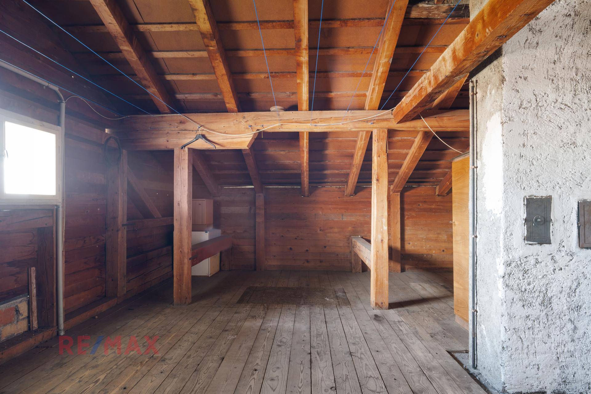Unausgebauter Dachboden mit sichtbaren Holzbalken und Holzfußboden.