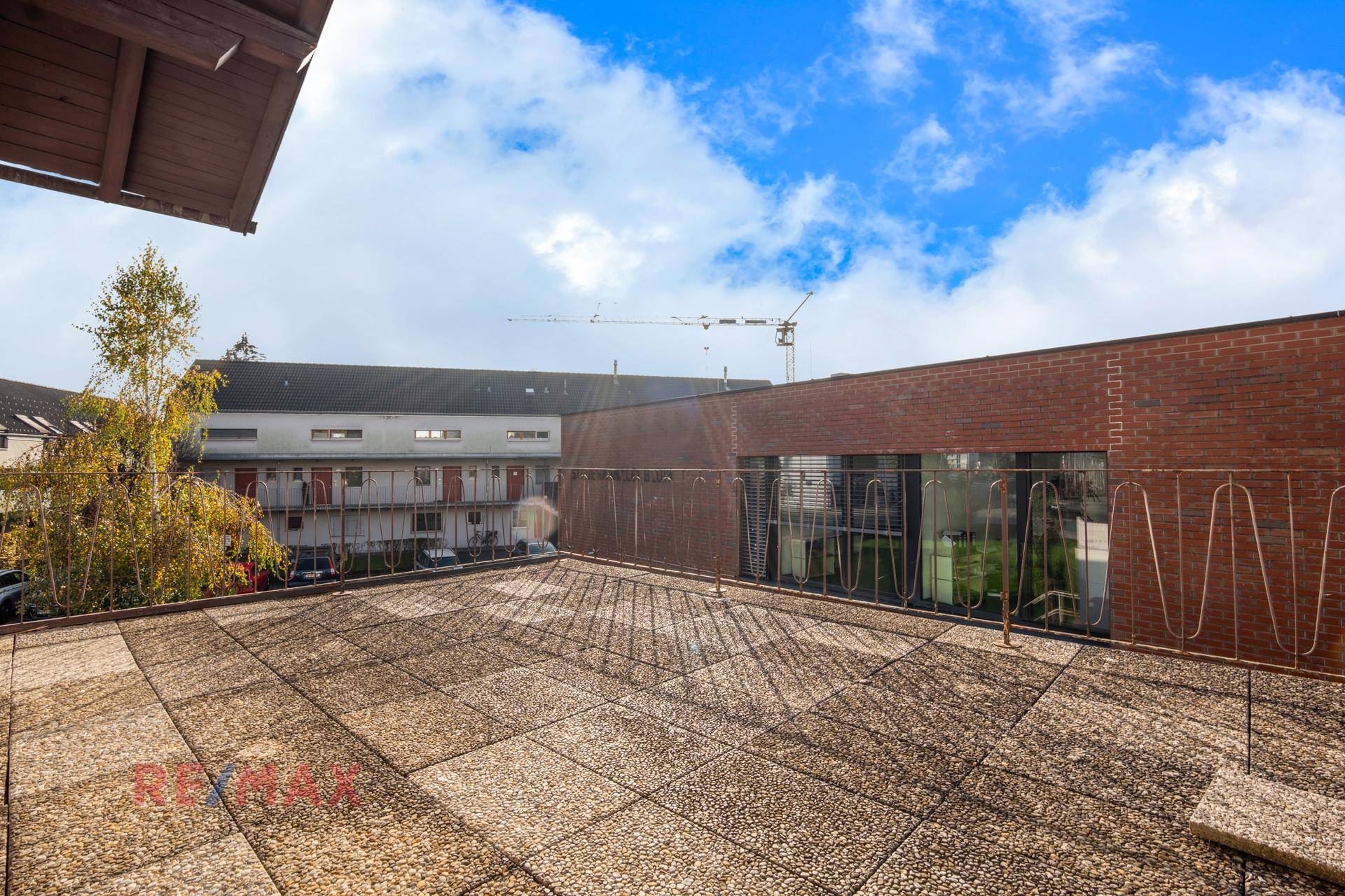 Große Dachterrasse mit Steinplatten und Blick auf die umliegenden Gebäude.