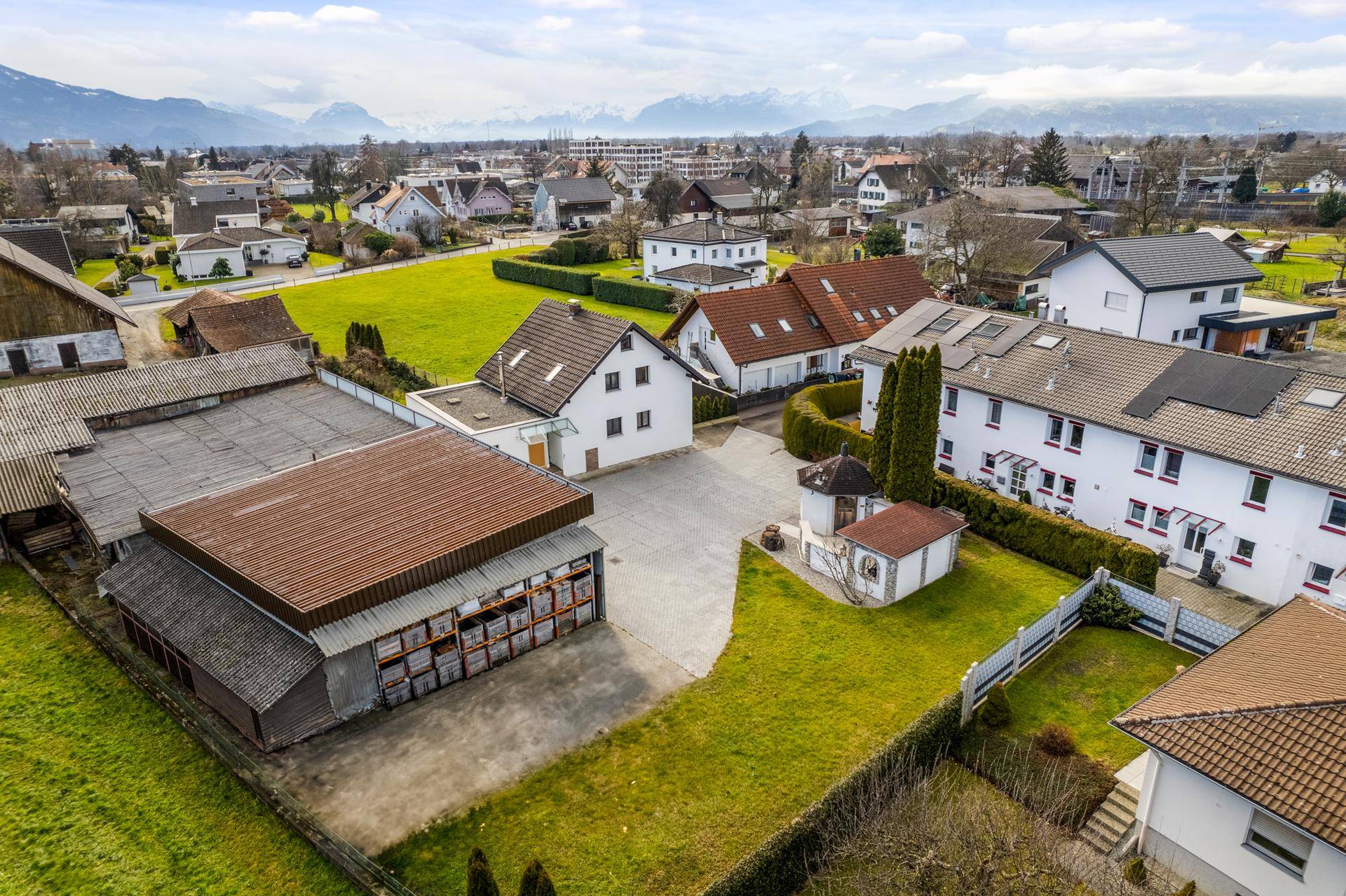 Luftaufnahme des Anwesens mit Wohnhaus, Nebengebäuden und umliegender grüner Landschaft.