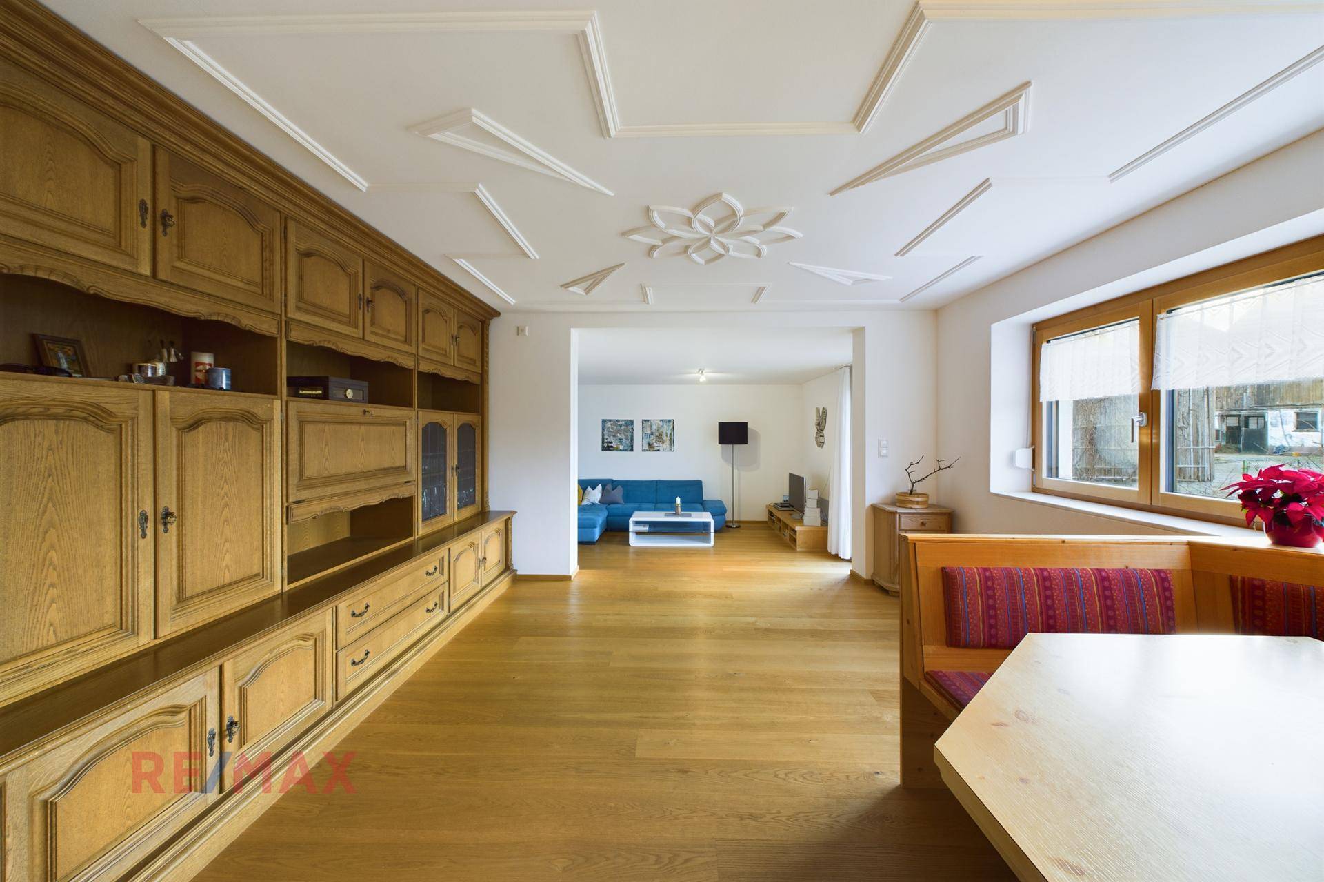 Essbereich mit Holzbänken und Blick in den hellen Wohnbereich mit Sofa.