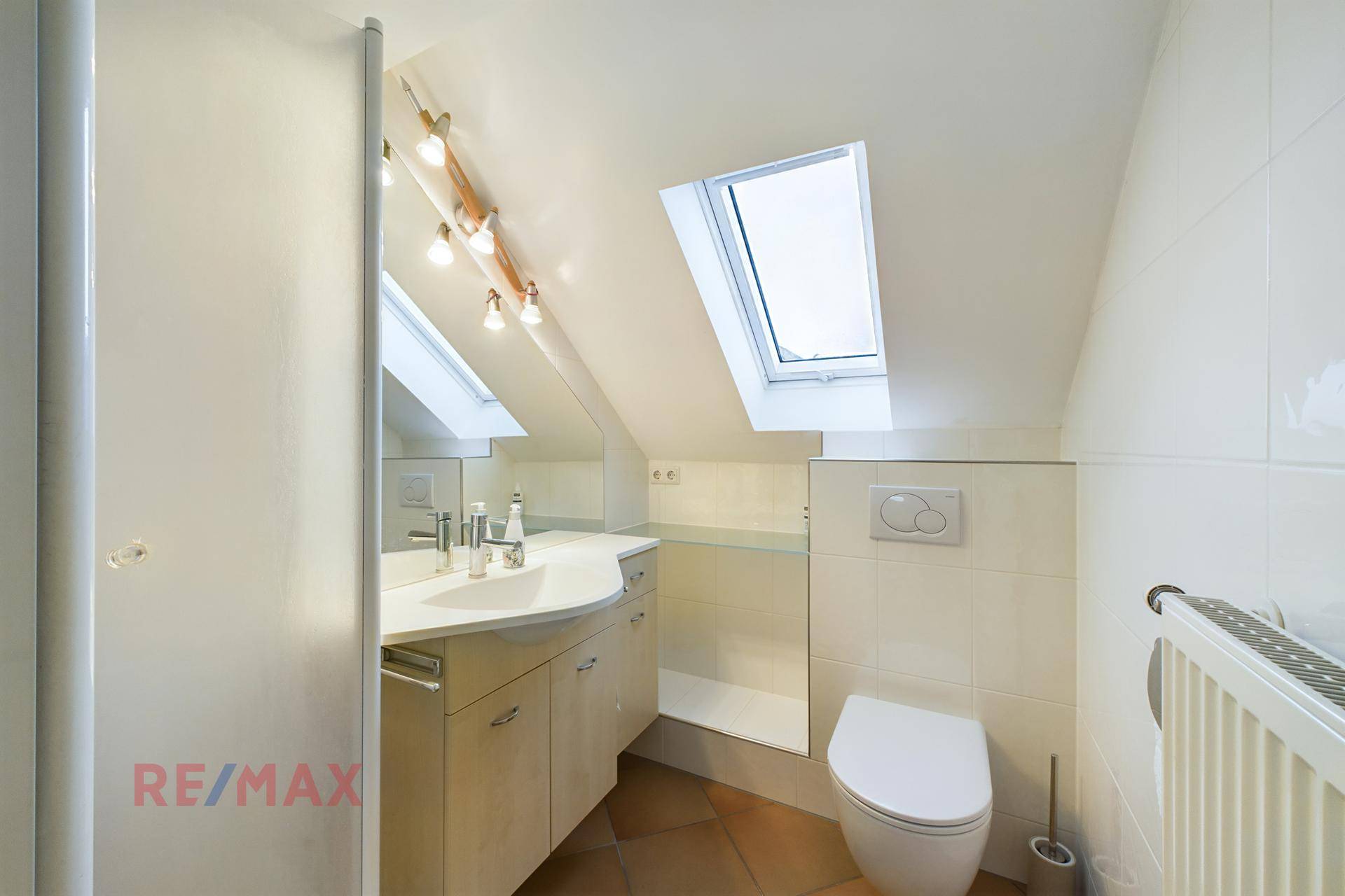 Badezimmer im Dachgeschoss mit Dachfenstern, Waschbecken und Toilette.