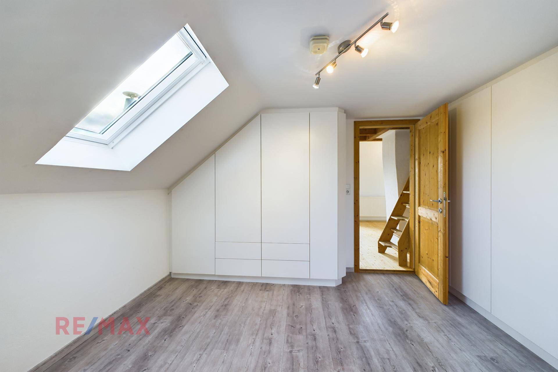 Schlafzimmer im Dachgeschoss mit Einbauschränken, Dachfenster und Laminatboden.