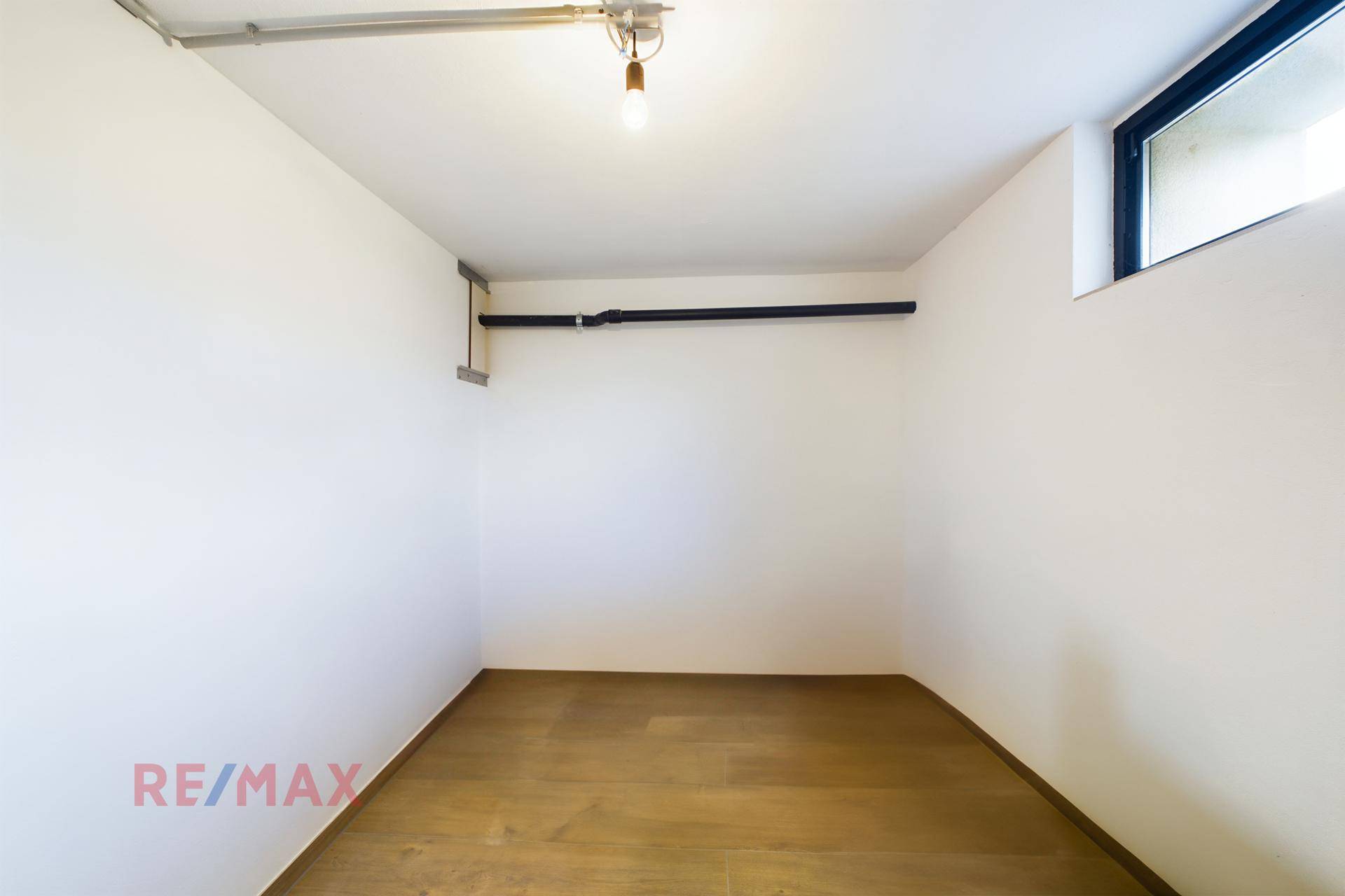Leerer Abstellraum im Keller mit Fenster und hellem Holzfußboden.