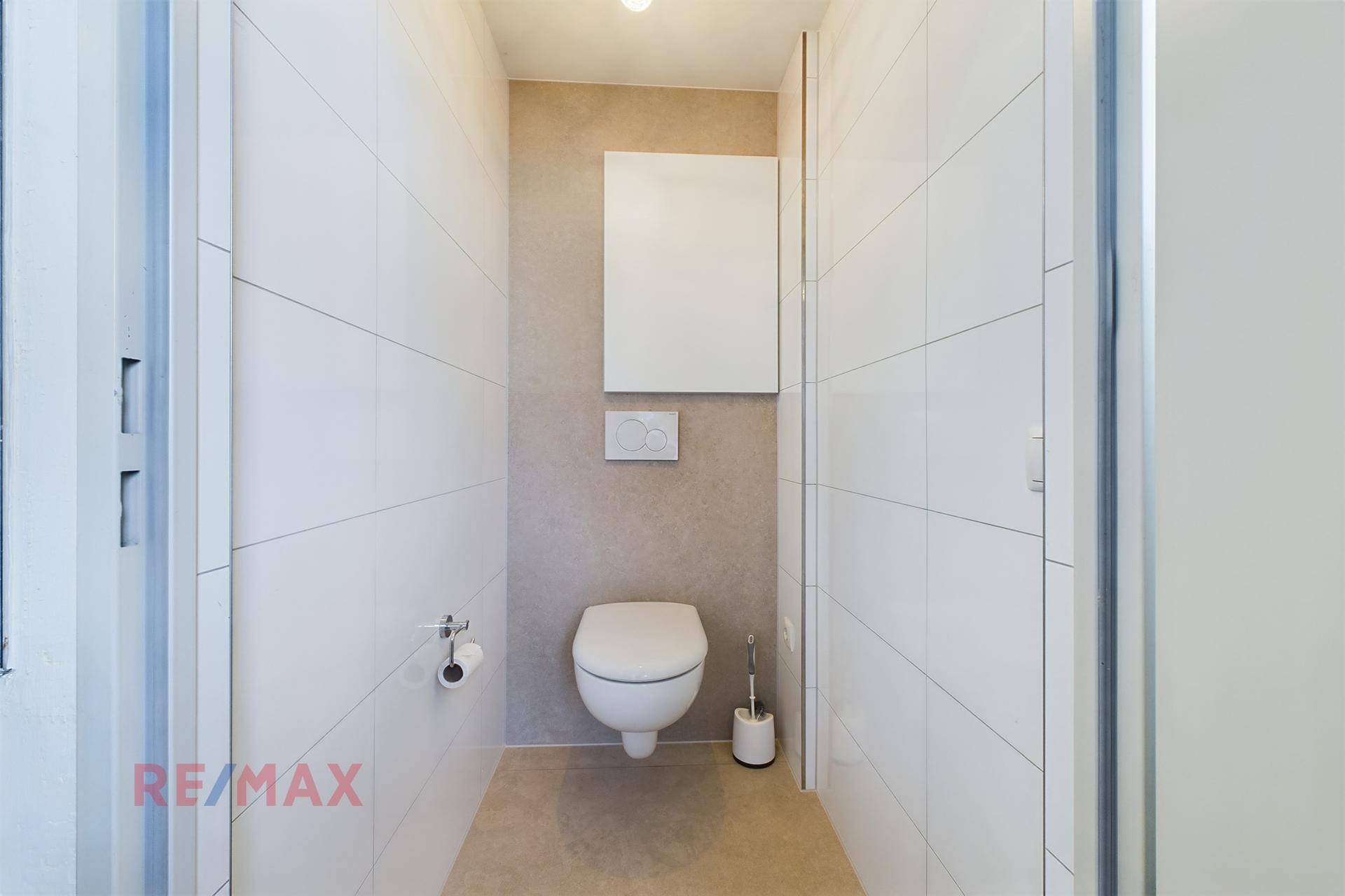 Kleines WC mit wandhängender Toilette und weißen Fliesen.