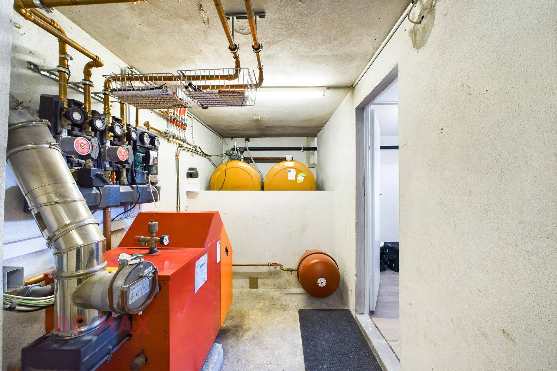 Heizungsraum im Keller mit Heizkessel, Öltanks und sichtbaren Rohrleitungen.